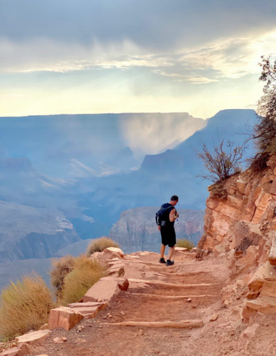 man hiking down steps over the horizon