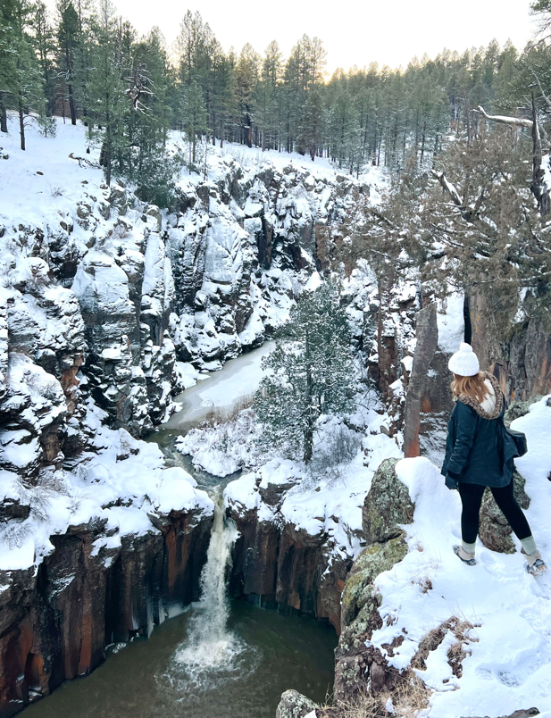 Woman Looking over Snowy Waterfall