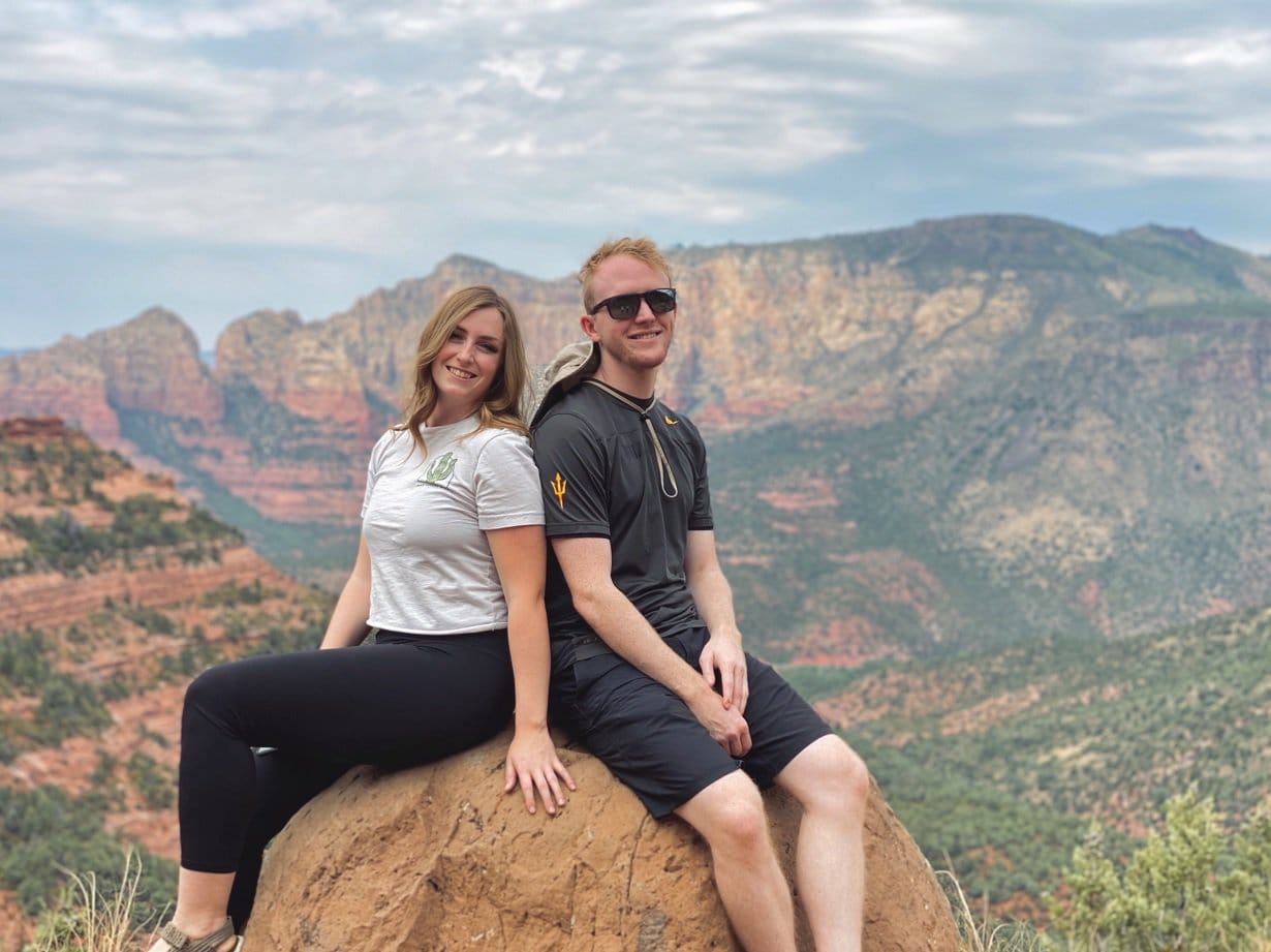 Couple Sitting on a Rock in Front of a View of Sedona Arizona