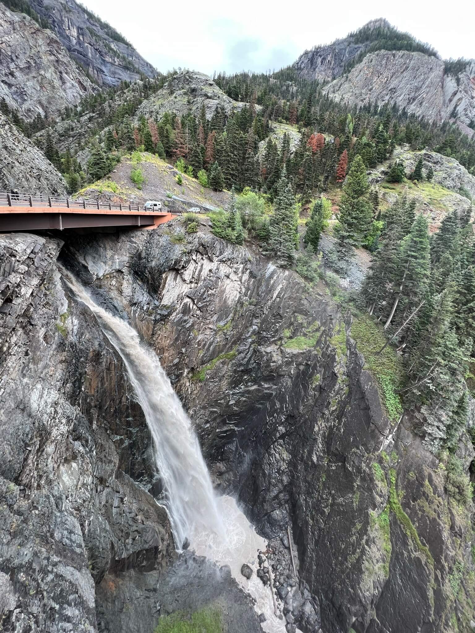 Waterfall in the Mountains with a Red Bridge