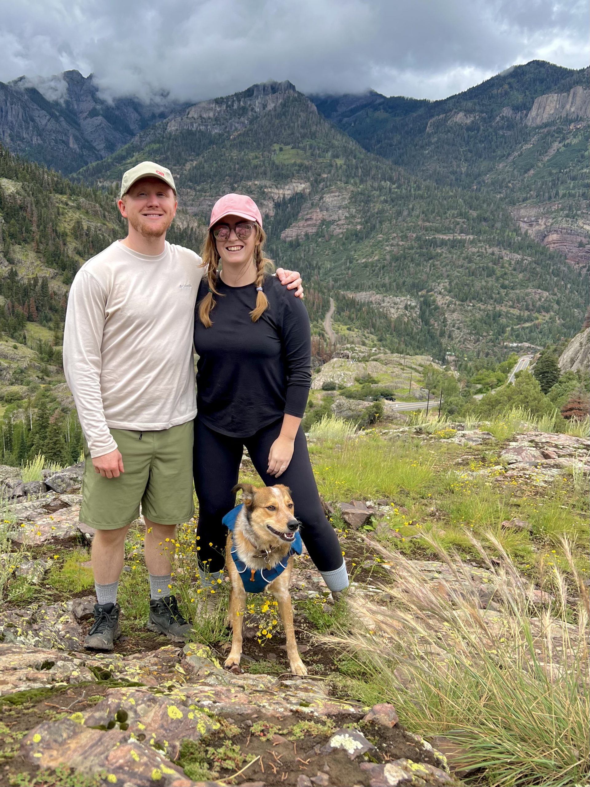 Two People and a Dog Standing in a Green Area