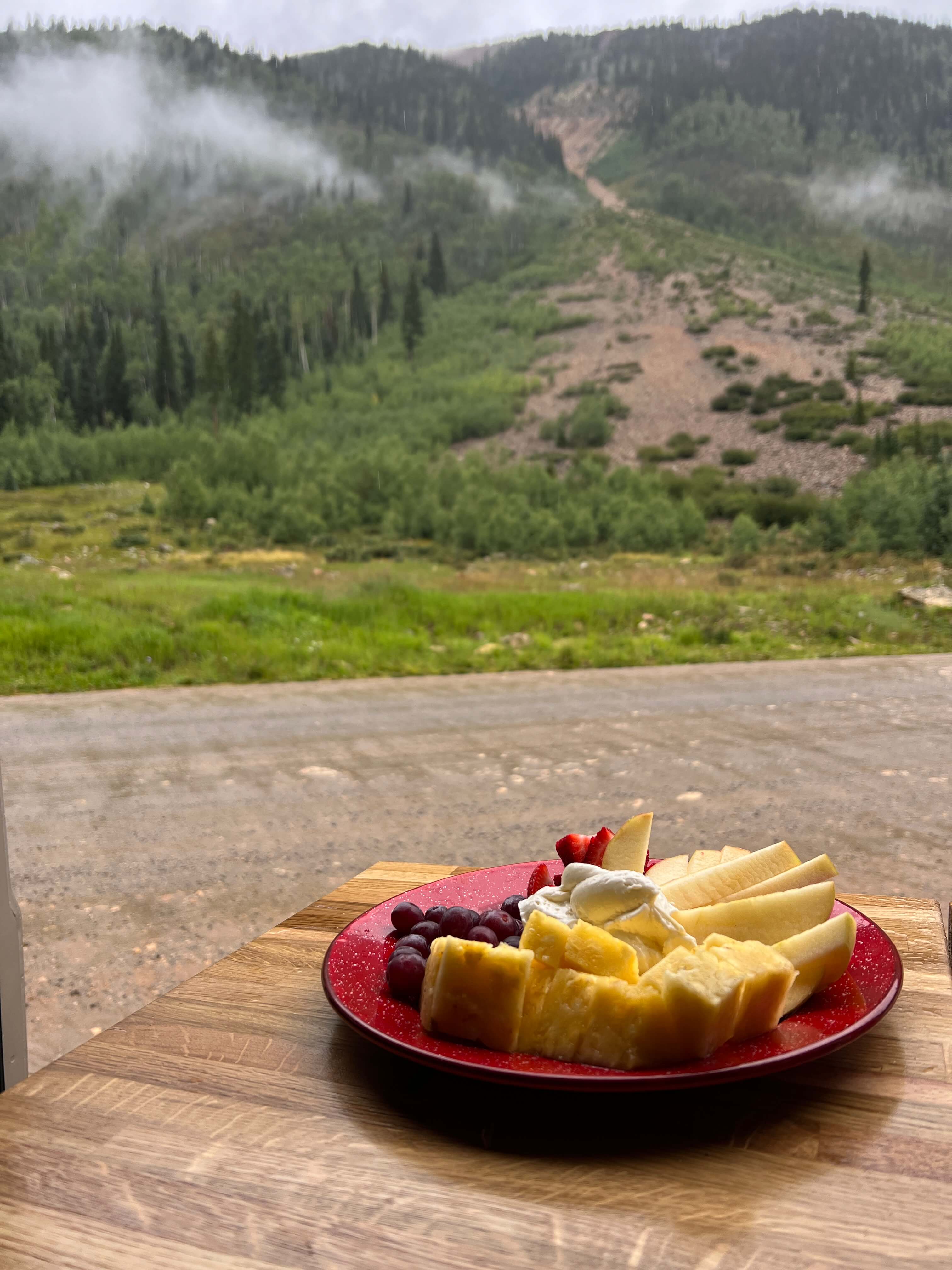 Red Plate of Food on Butcher Block with Mountains in the Background