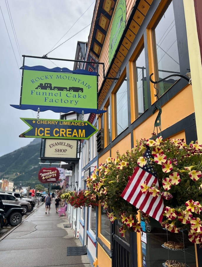 Green Sign Saying Rocky Mountain Funnel Cake Factory on a Cloudy Day