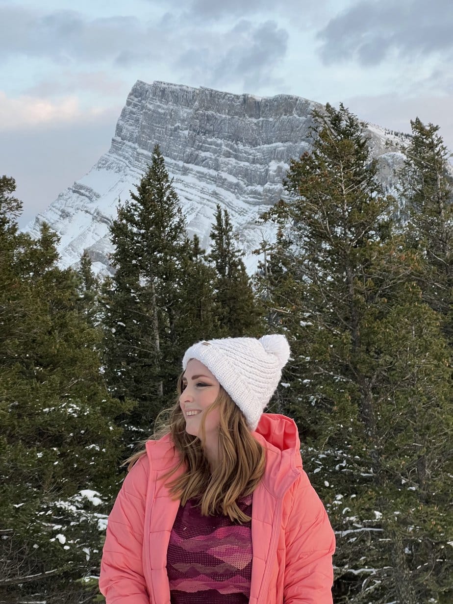 Girl in a Pink Coat Smiling in front of Winter Mountains