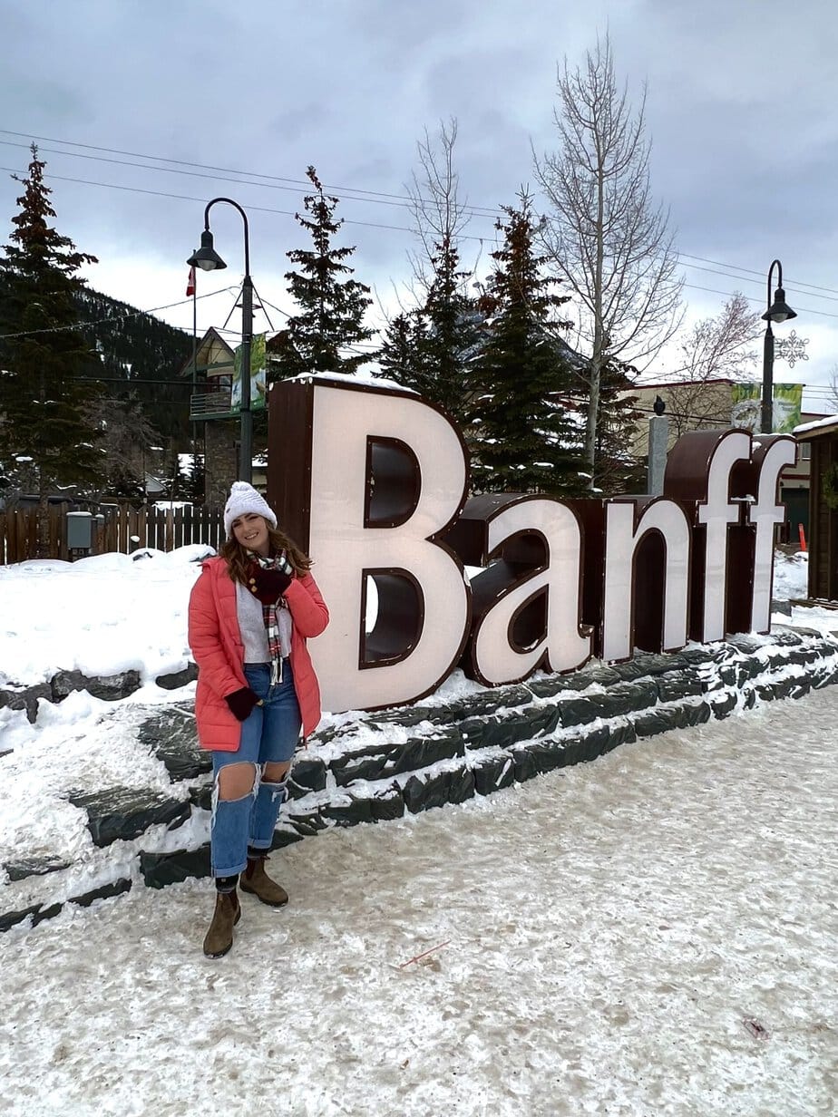 Girl in a Pink Coat Standing in Front of a City Sign