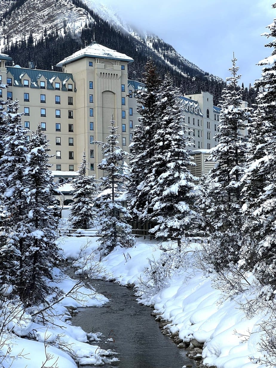 Tall Multi-Story Tan Hotel in the Middle of Trees Covered in Snow