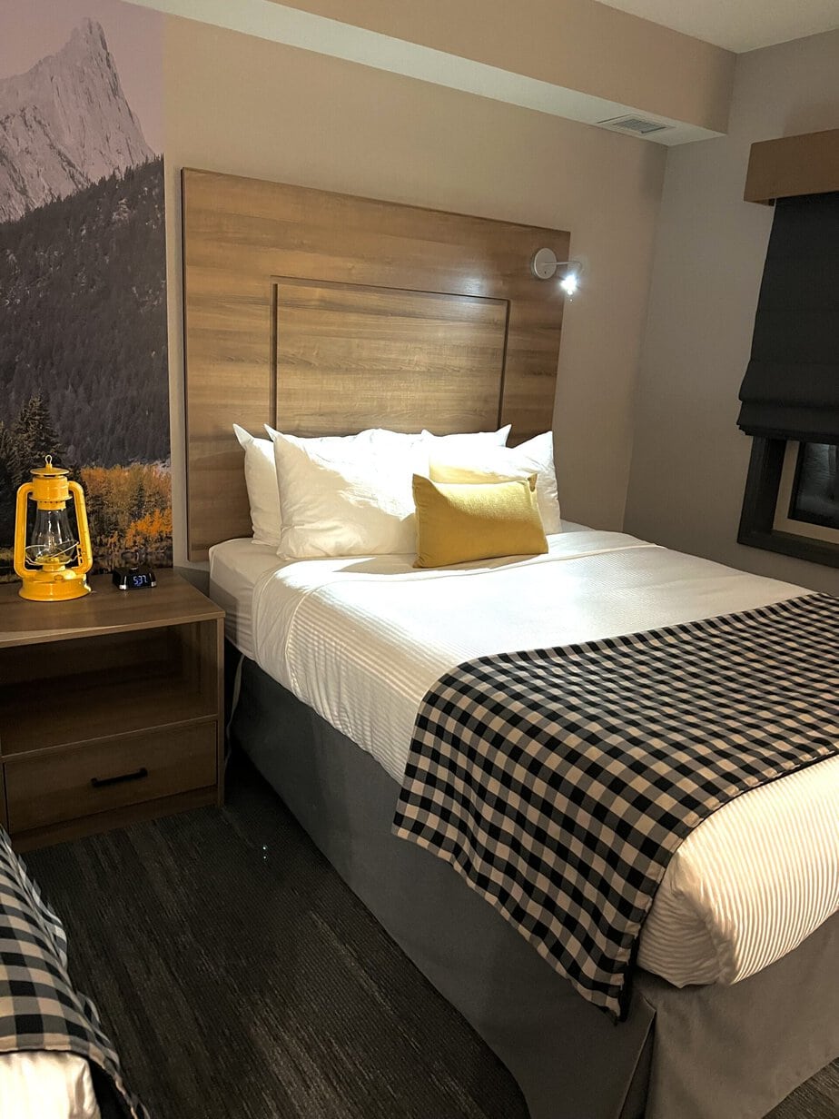 Hotel Room with Yellow Accents and a Queen Bed with Plaid Cover