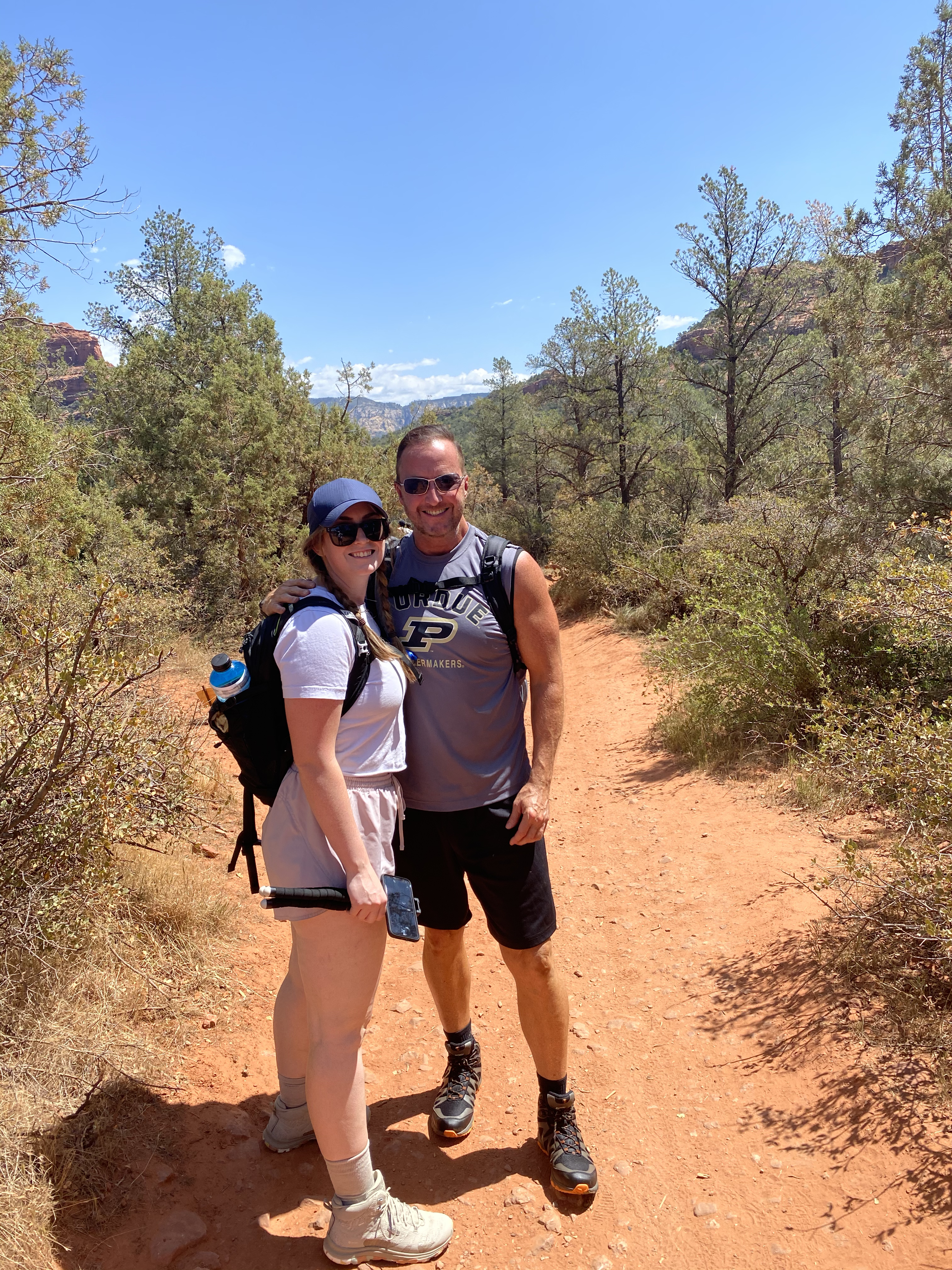 Girl and Dad Standing on Orange Sand on a Clear Blue Day