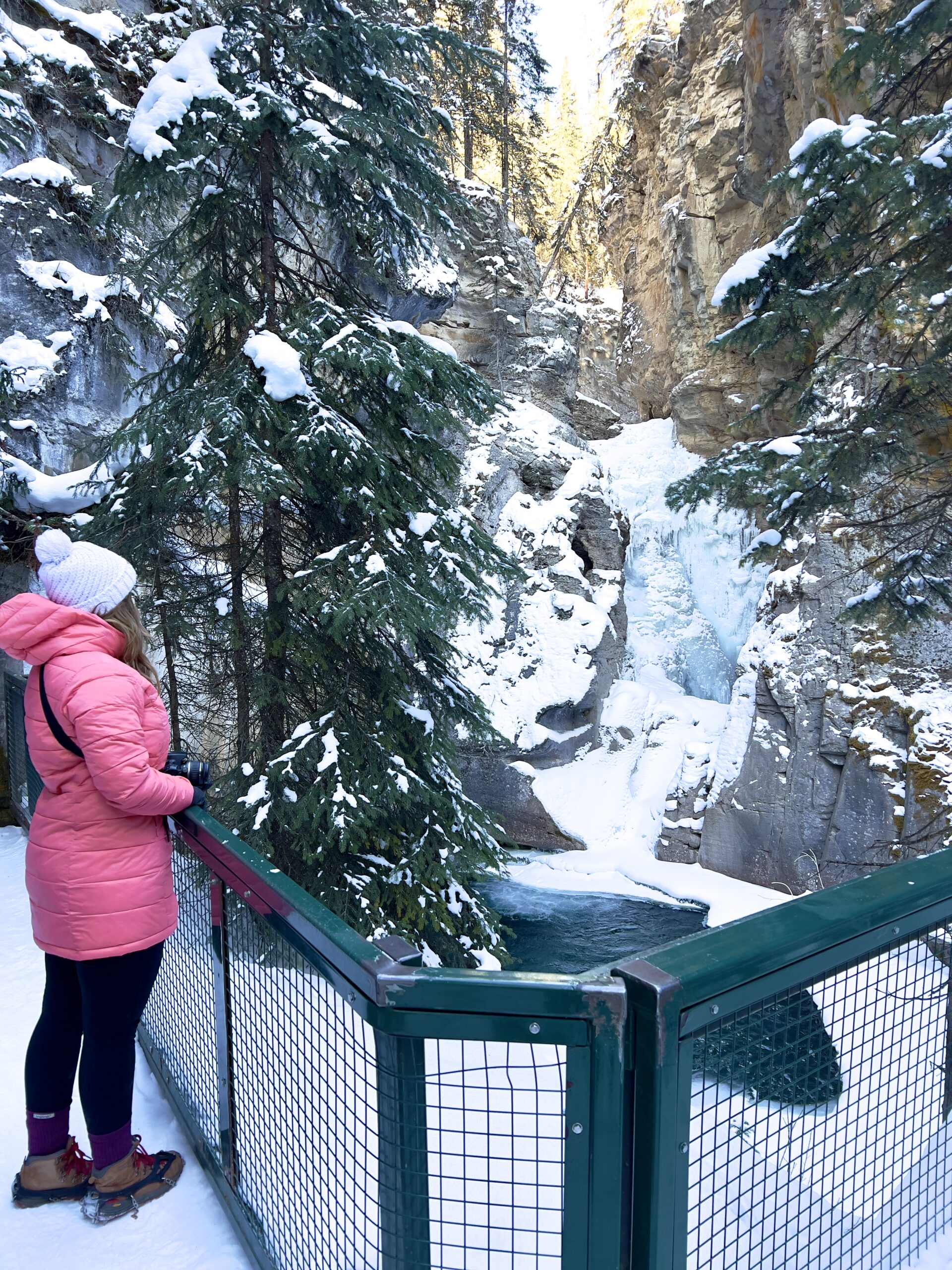 Girl in Pink Coat Standing by Frozen Waterfall