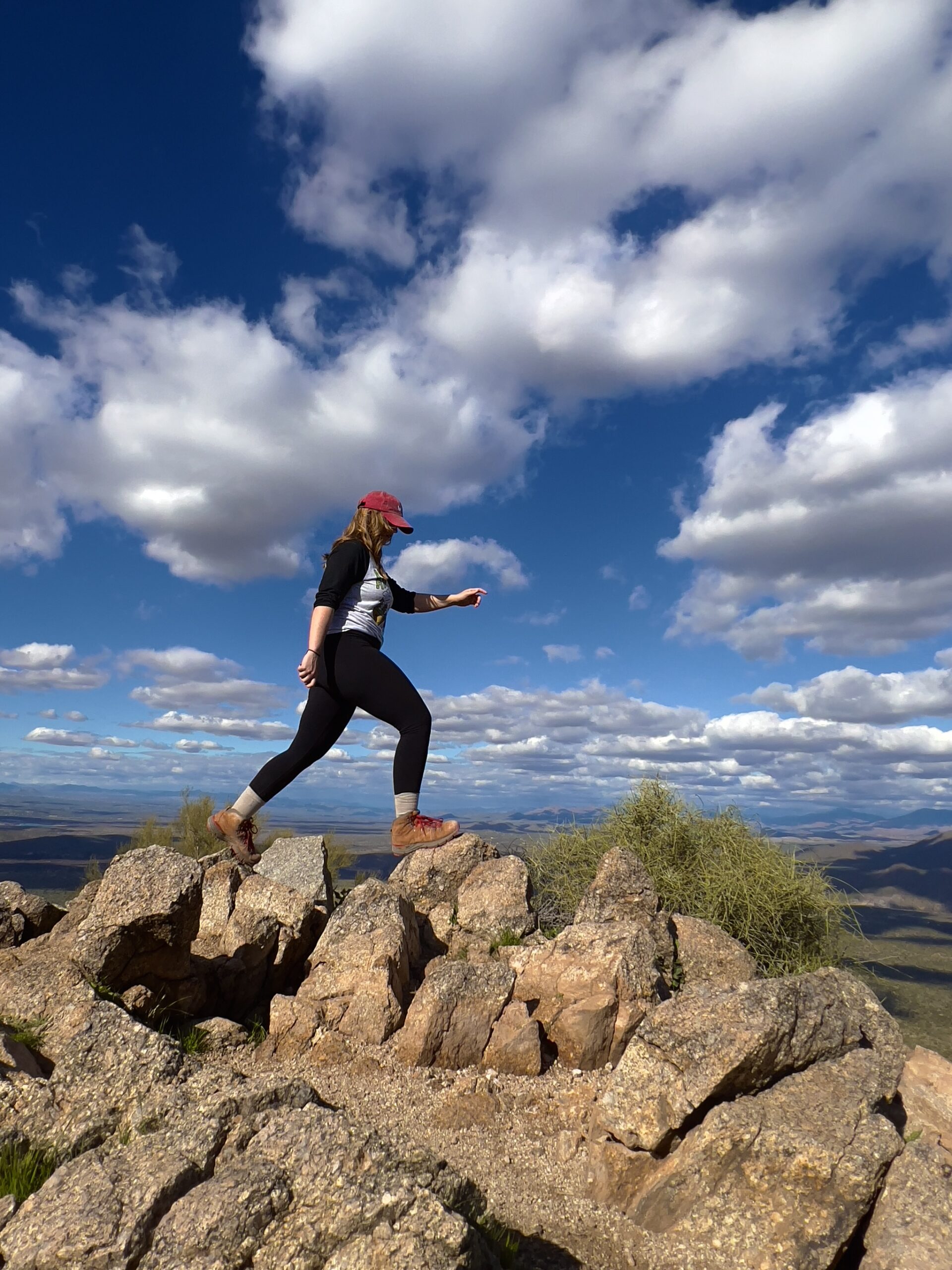 Girl Stepping up on Rocks on a Mountain Summit in the Middle of the Day.