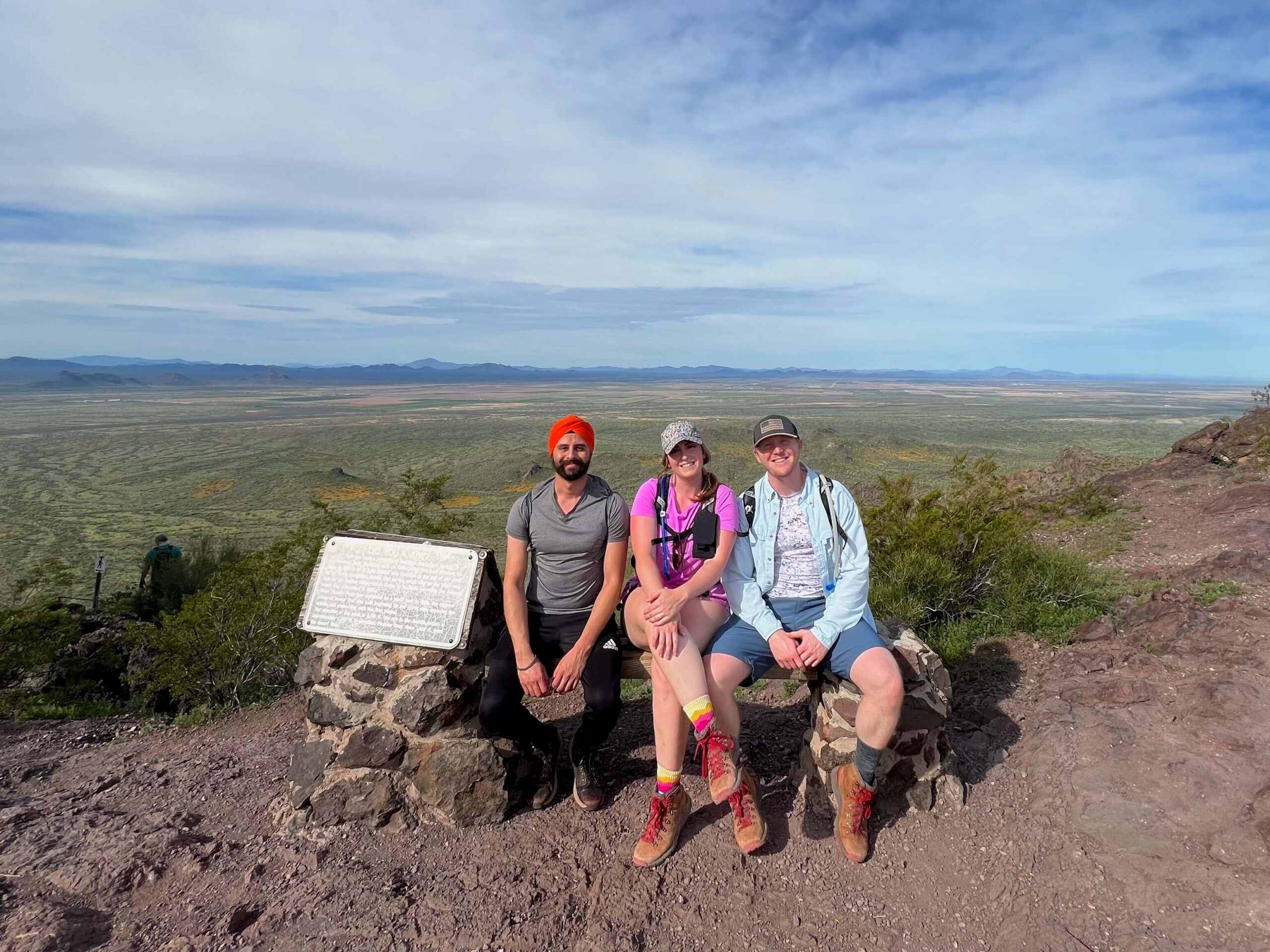 Three People sitting on top of a bench on the mountain