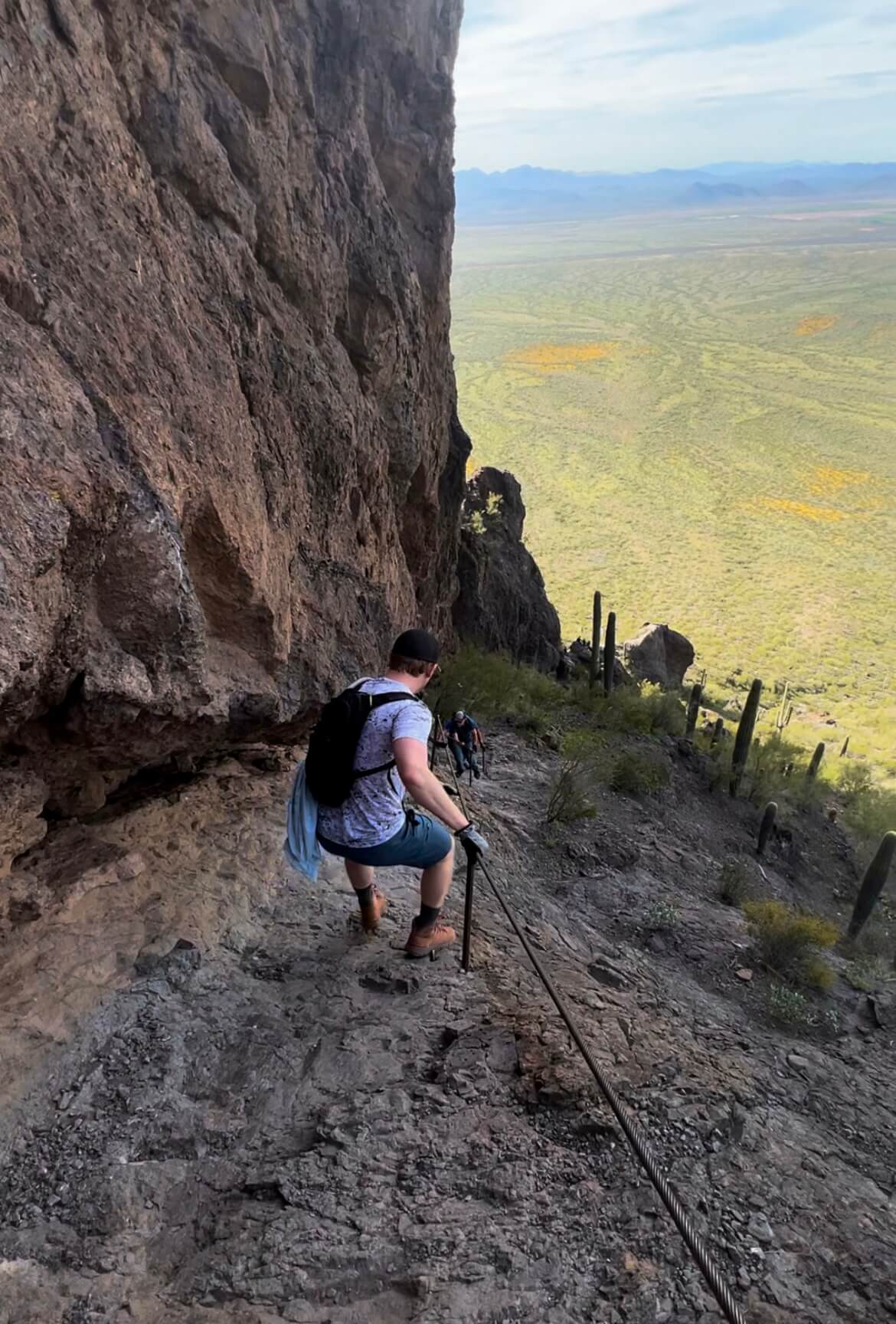 Man Climbing Down Mountain Holding onto a Rod