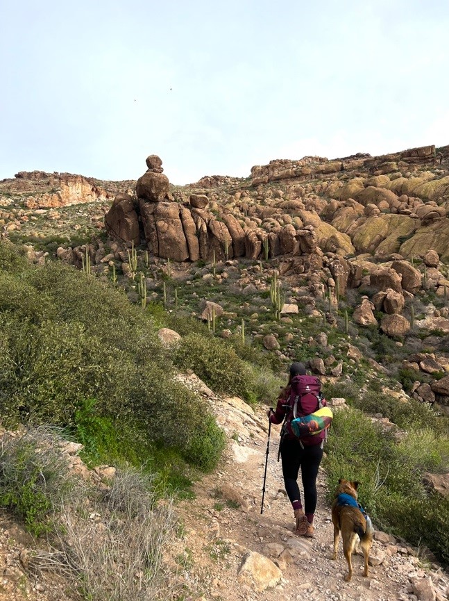 Girl in Maroon Backpack with Dog Hiking Near Rocks