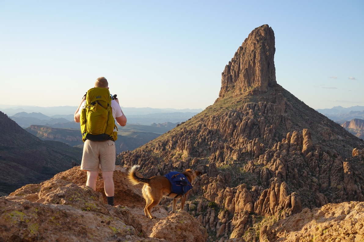 man standing with dog at an overlook in the rocky desert
