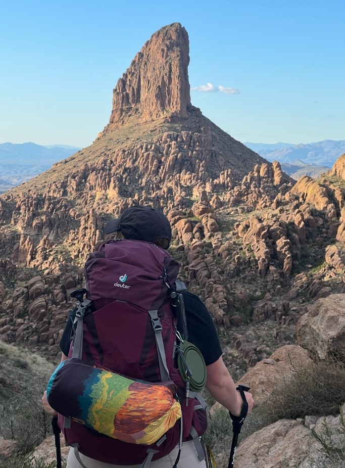 Girl with Maroon Backpack In Front of Weaver's Needle