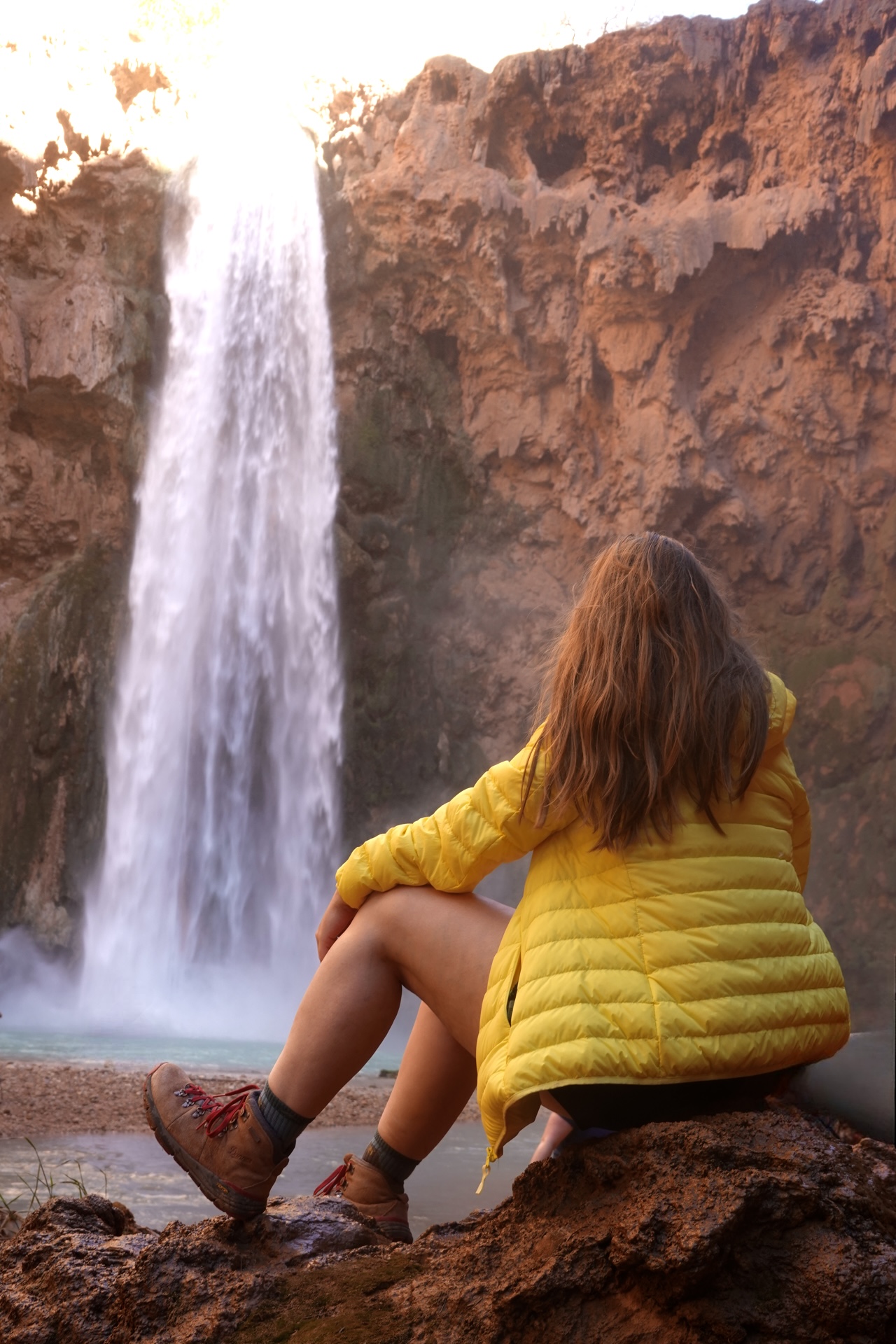 Girl in a Yellow Coat in front of a tall desert waterfall
