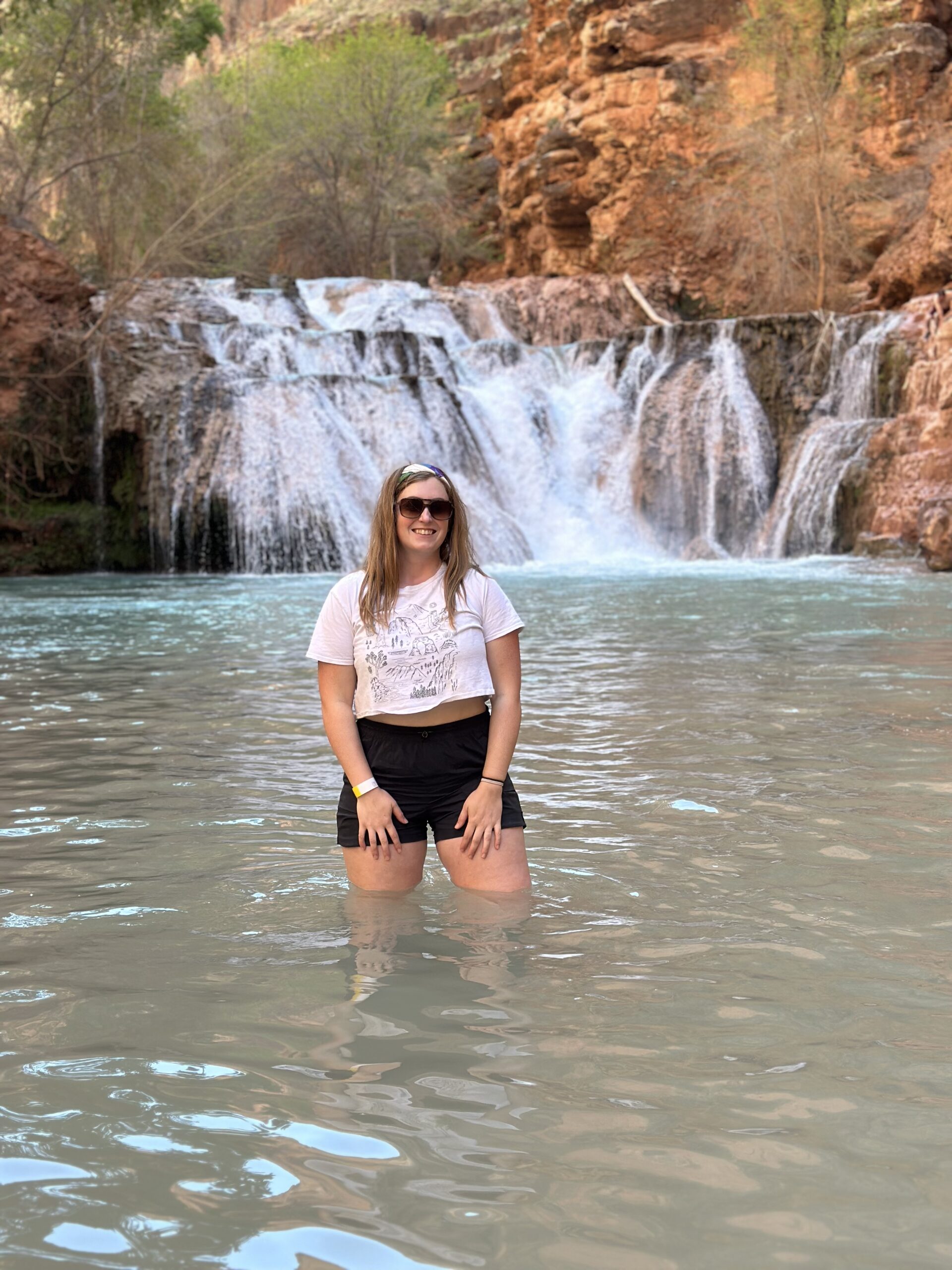 Girl Standing in Water by a Waterfall