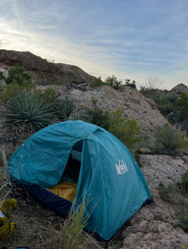 blue REI tent nuzzled in rocks