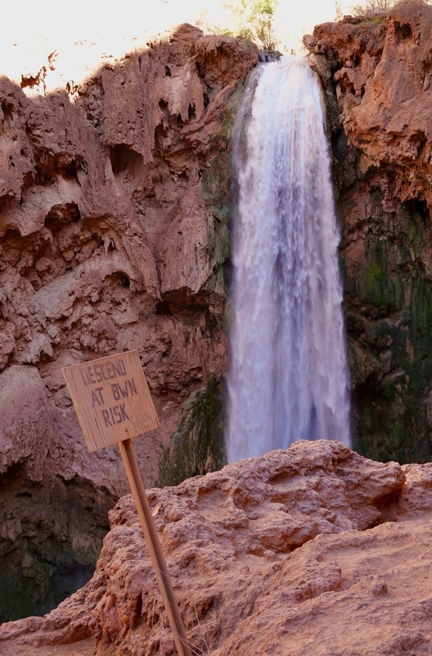sign stating descend at own risk by a waterfall