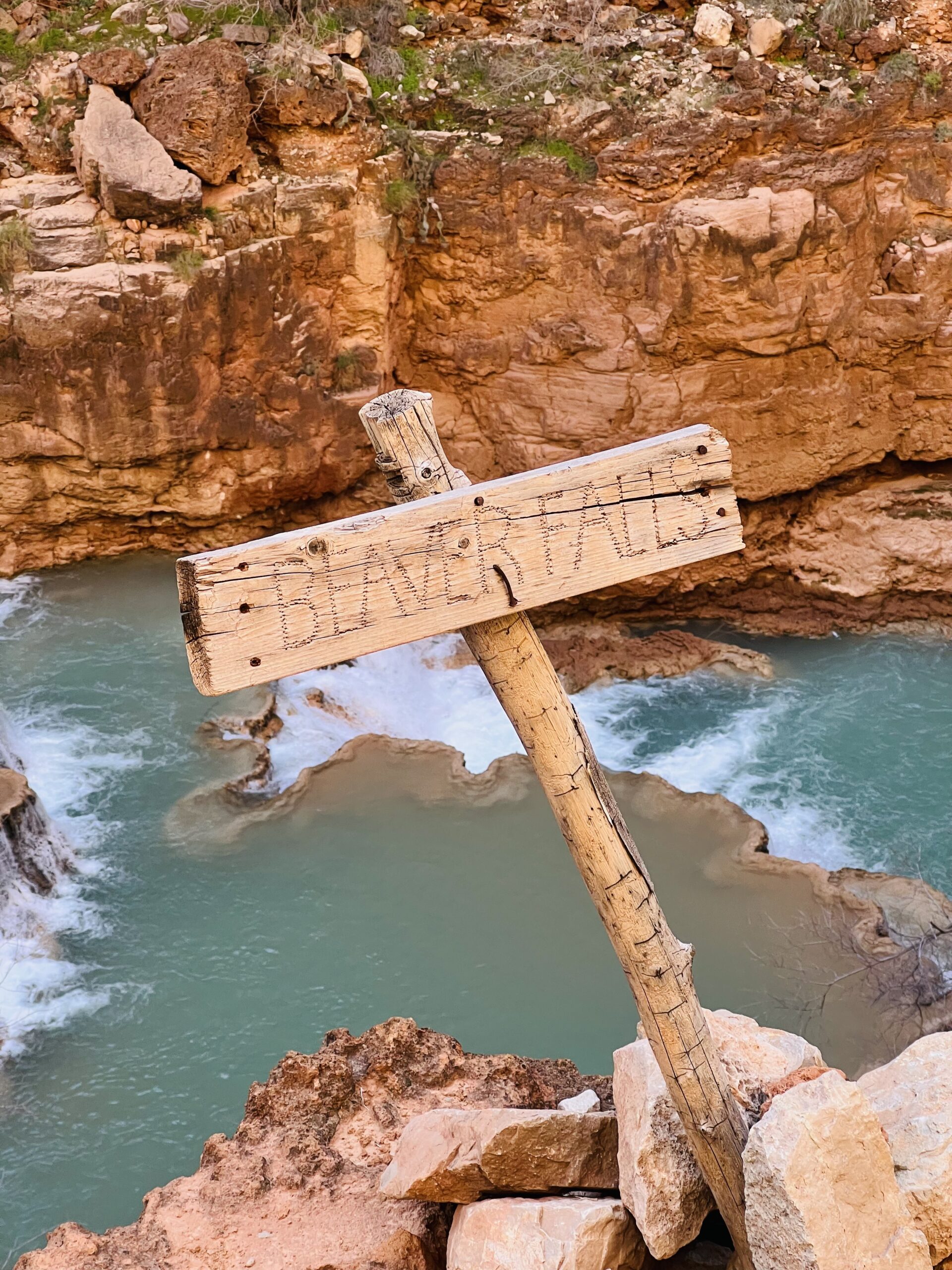 Wooden Sign Near a Waterfall that says beaver falls