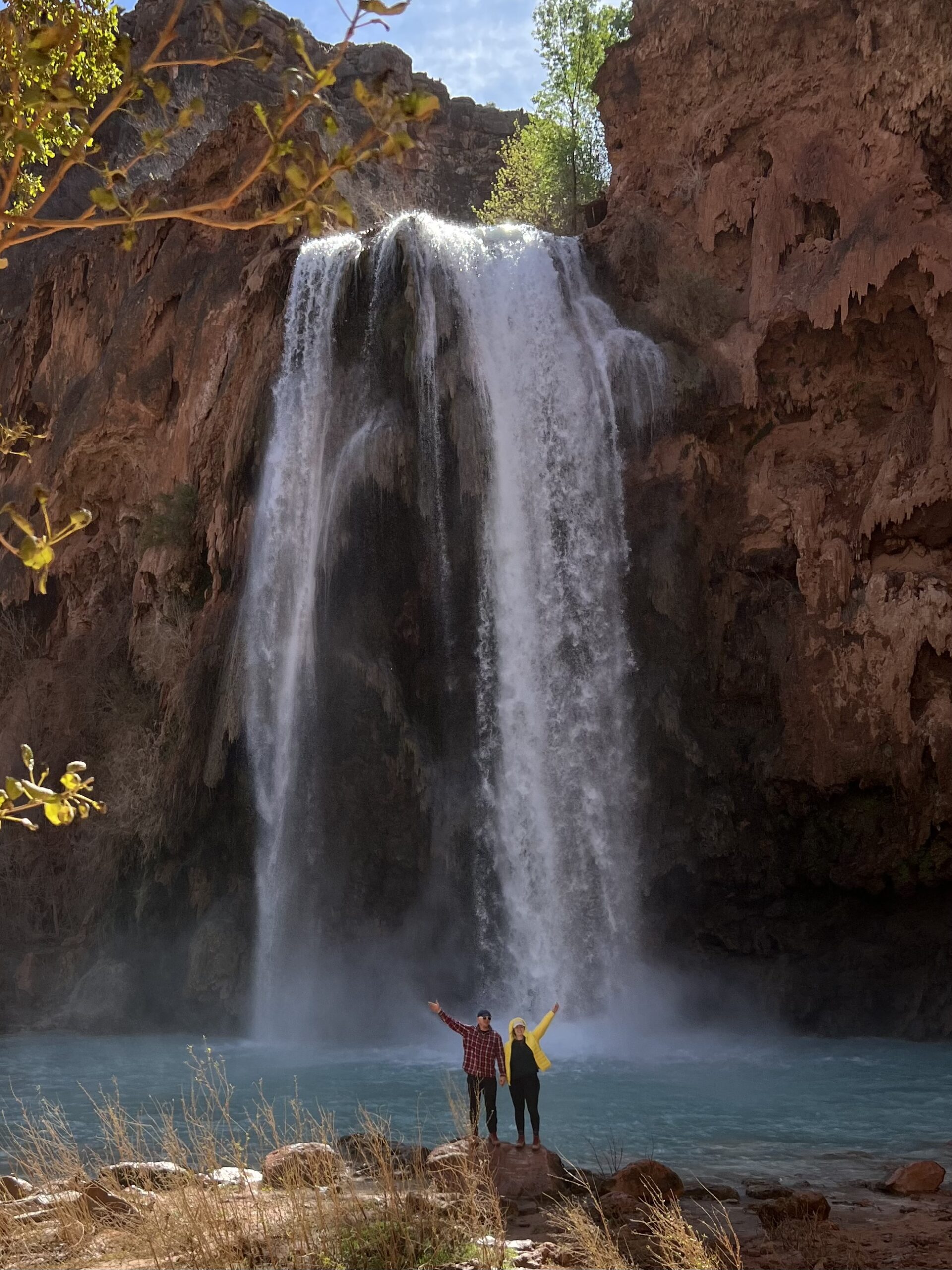 Two People Standing at the Base of a Large Waterfall