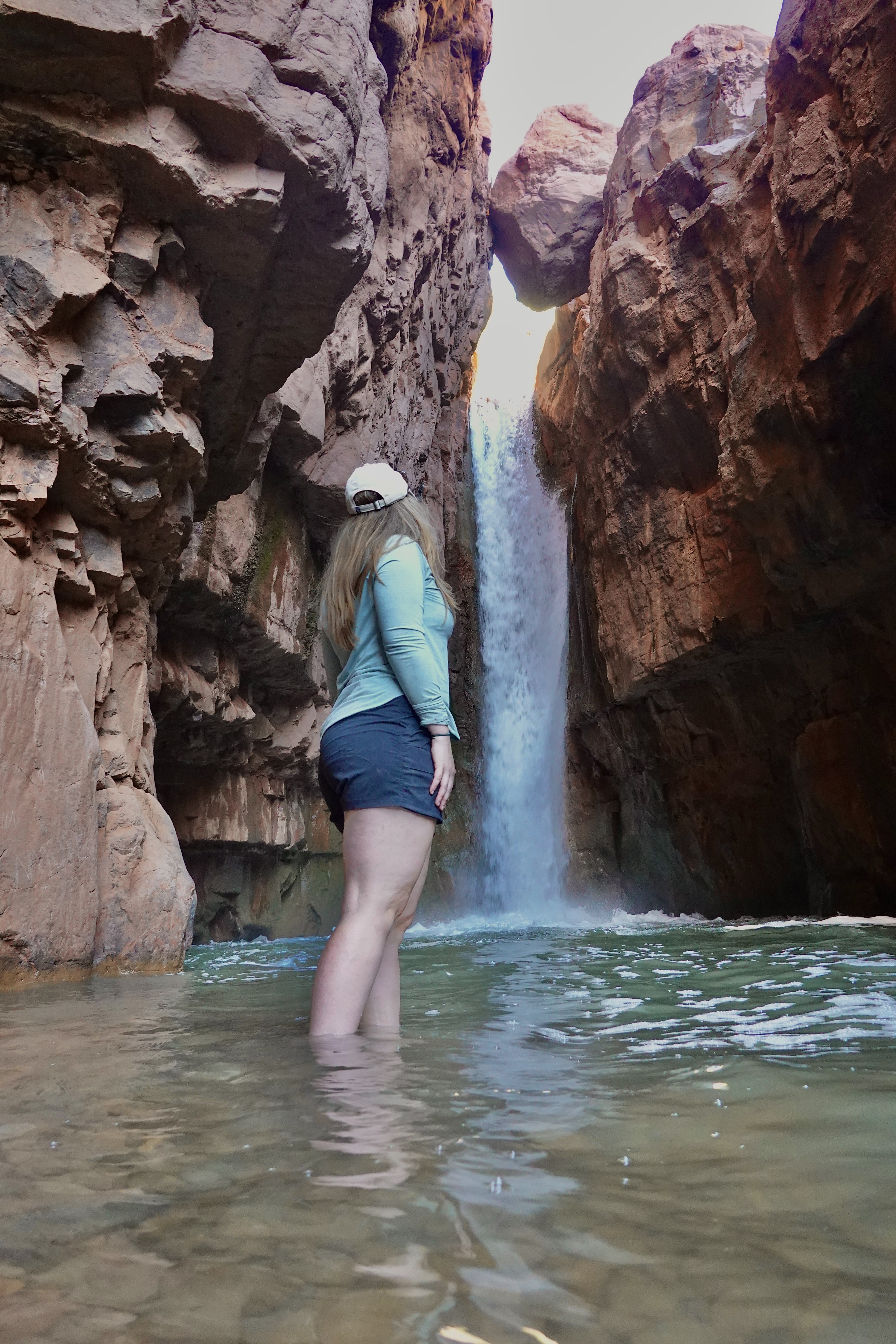 Girl Standing in the Water by a Waterfall