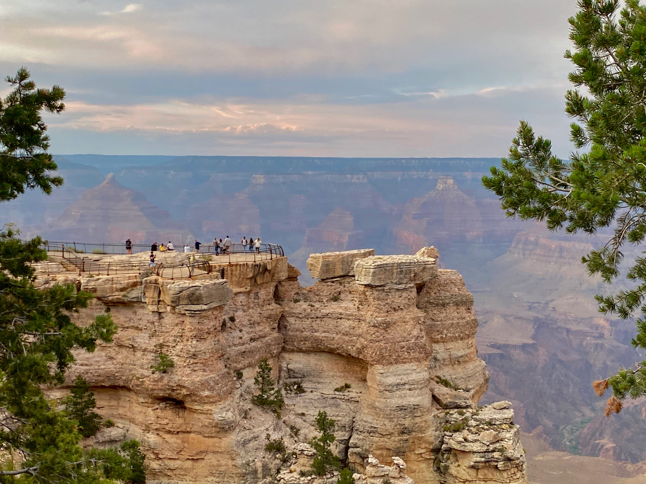 a canyon with people walking on the top with a fence in view