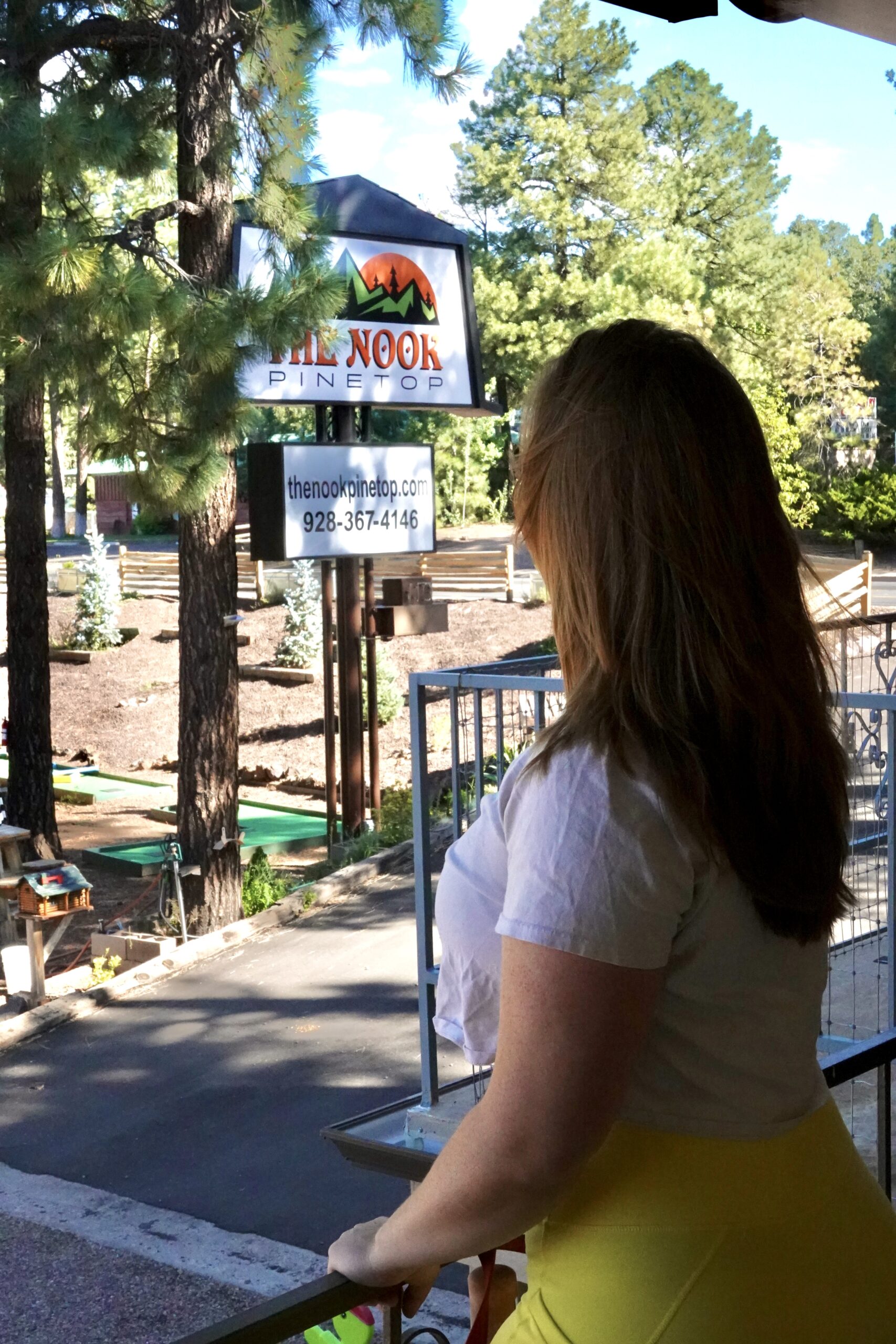 girl looking at a sign saying the nook in the forest