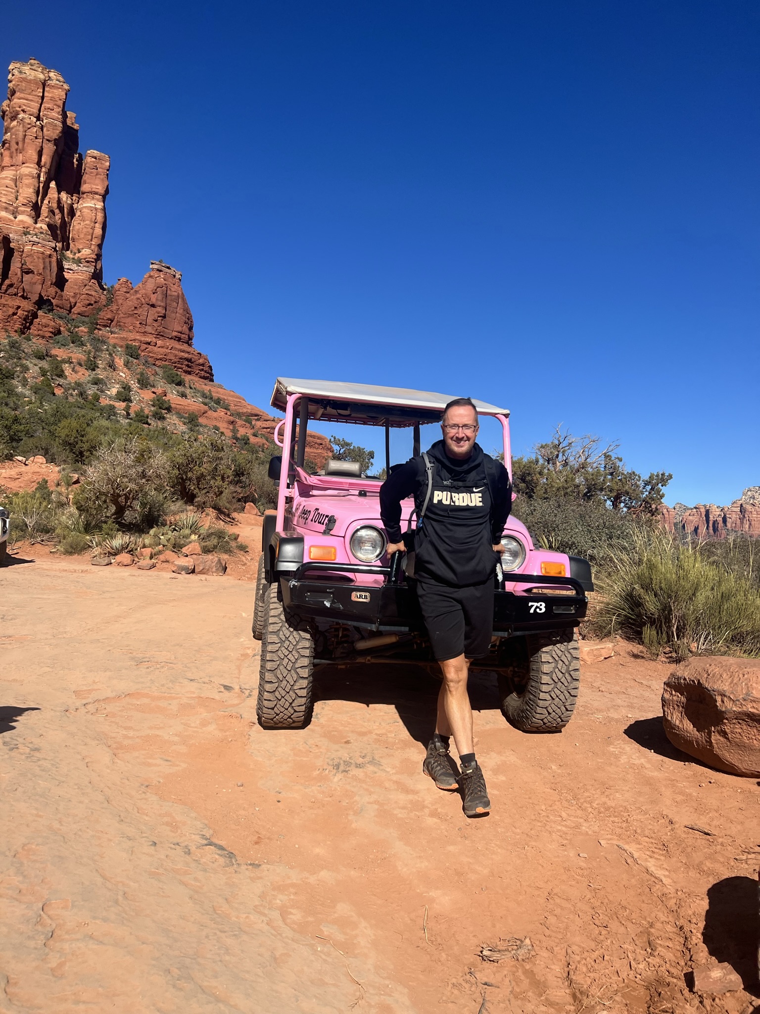 man in black in front of a pink jeep in sedona