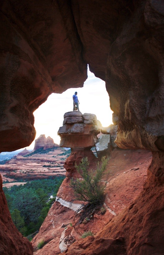 man standing on a rock through a cave