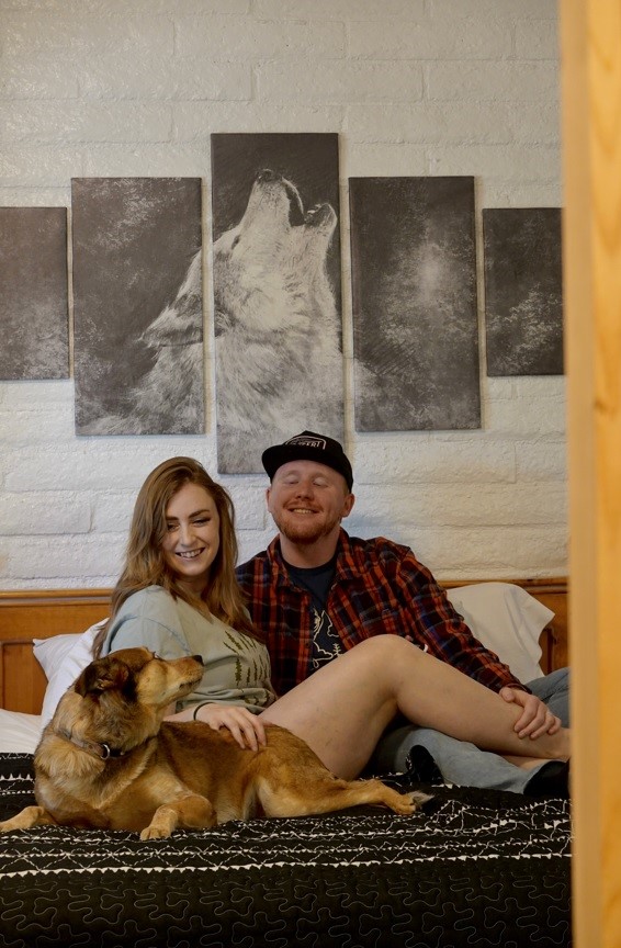 two people in a bed with a dog