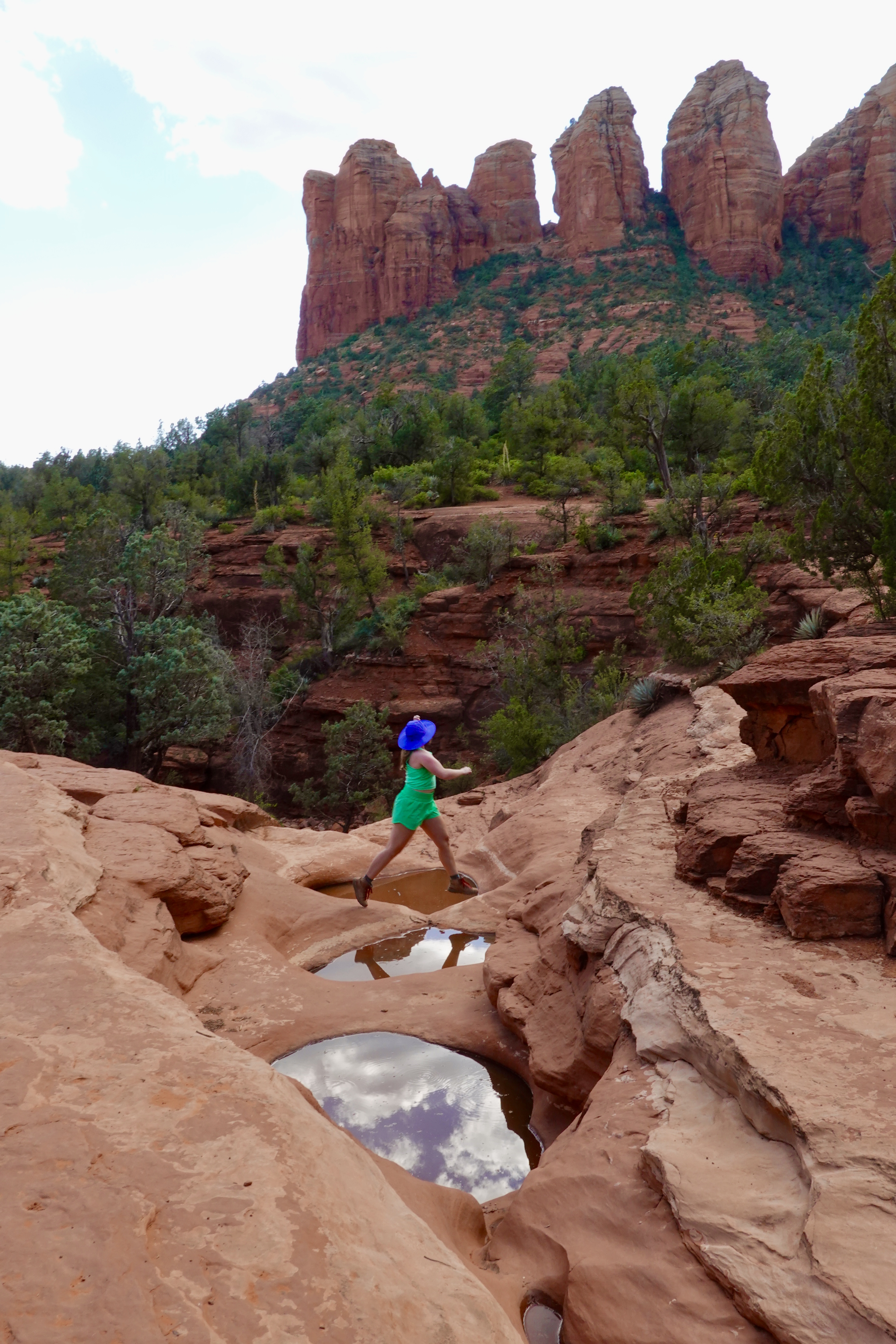 girl in green jumping over a pool of water in sedona
