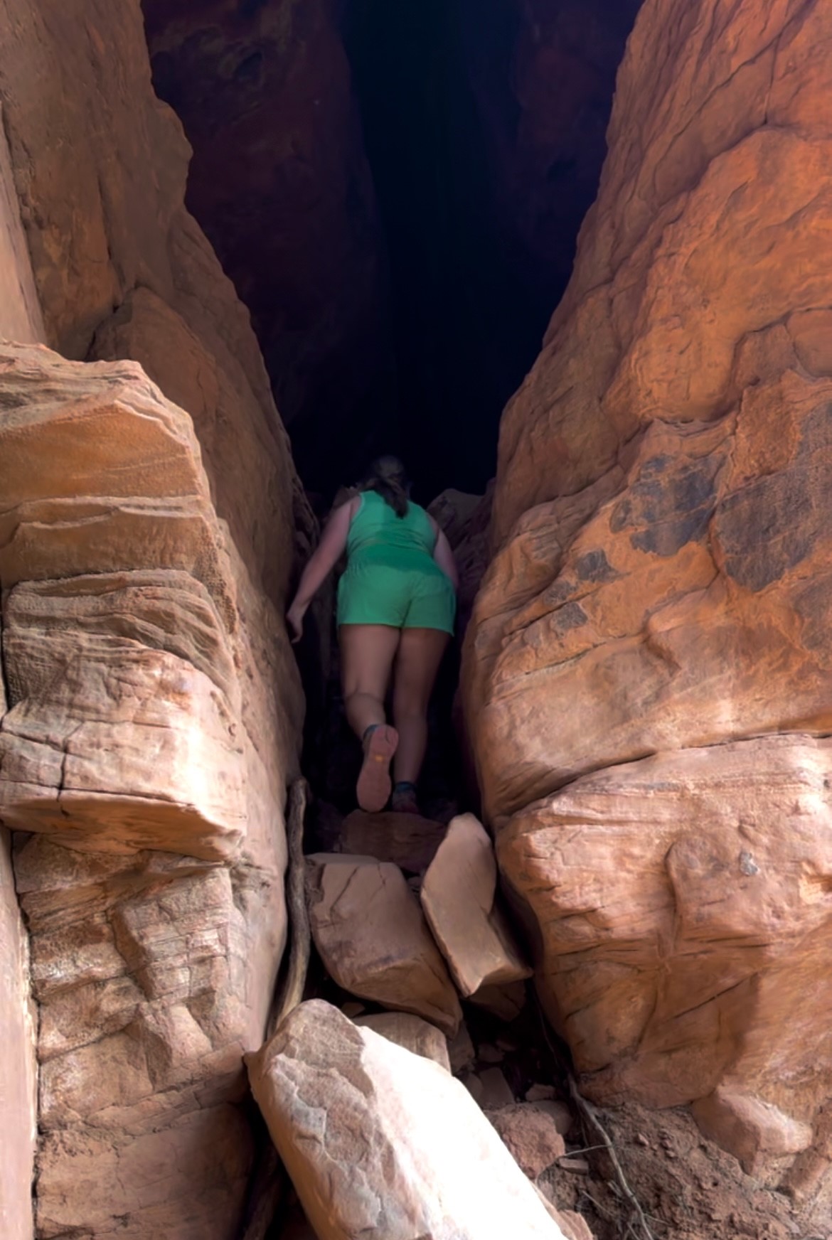 girl in green climbing into a cave