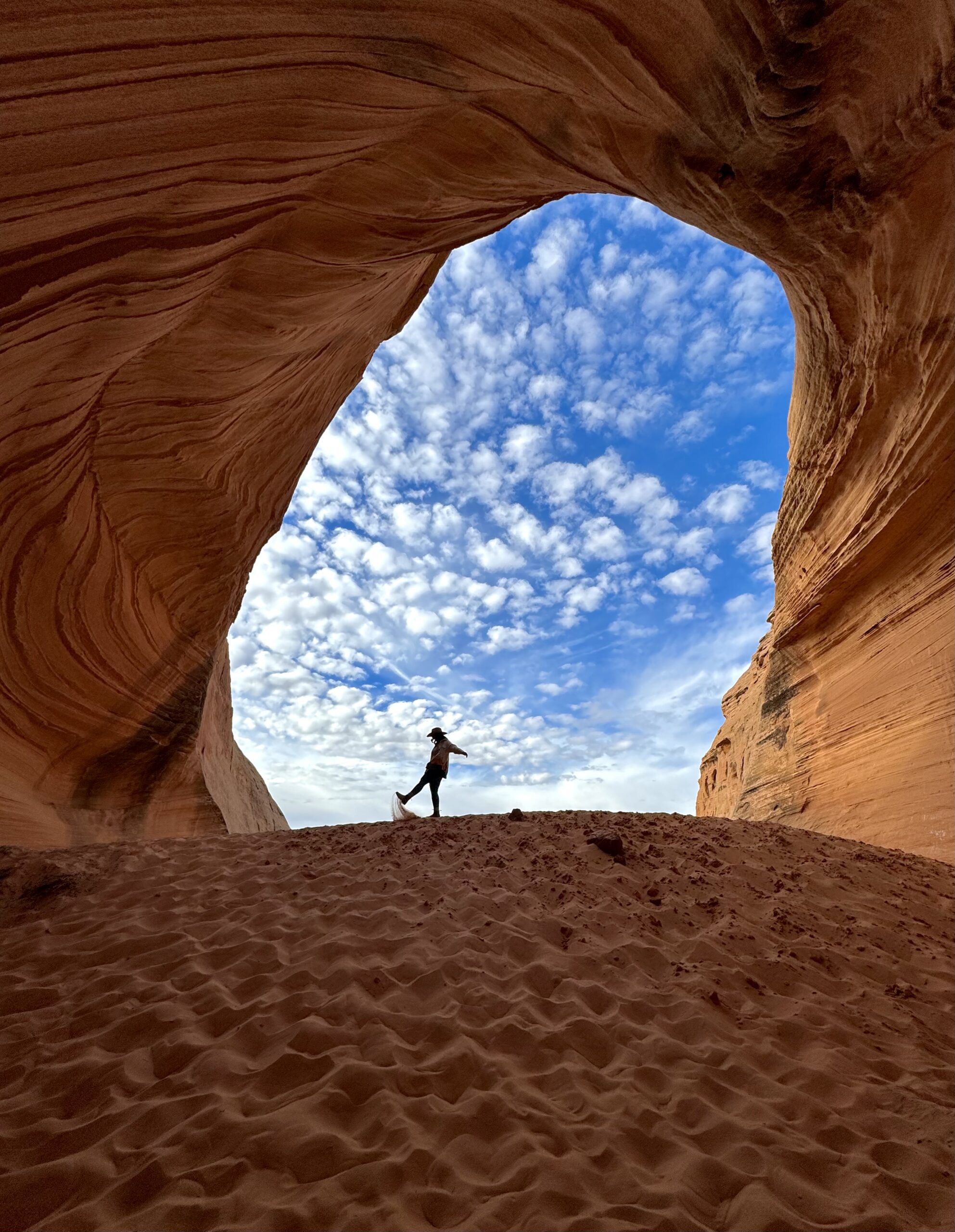 girl kicking sand in a sandstone cave