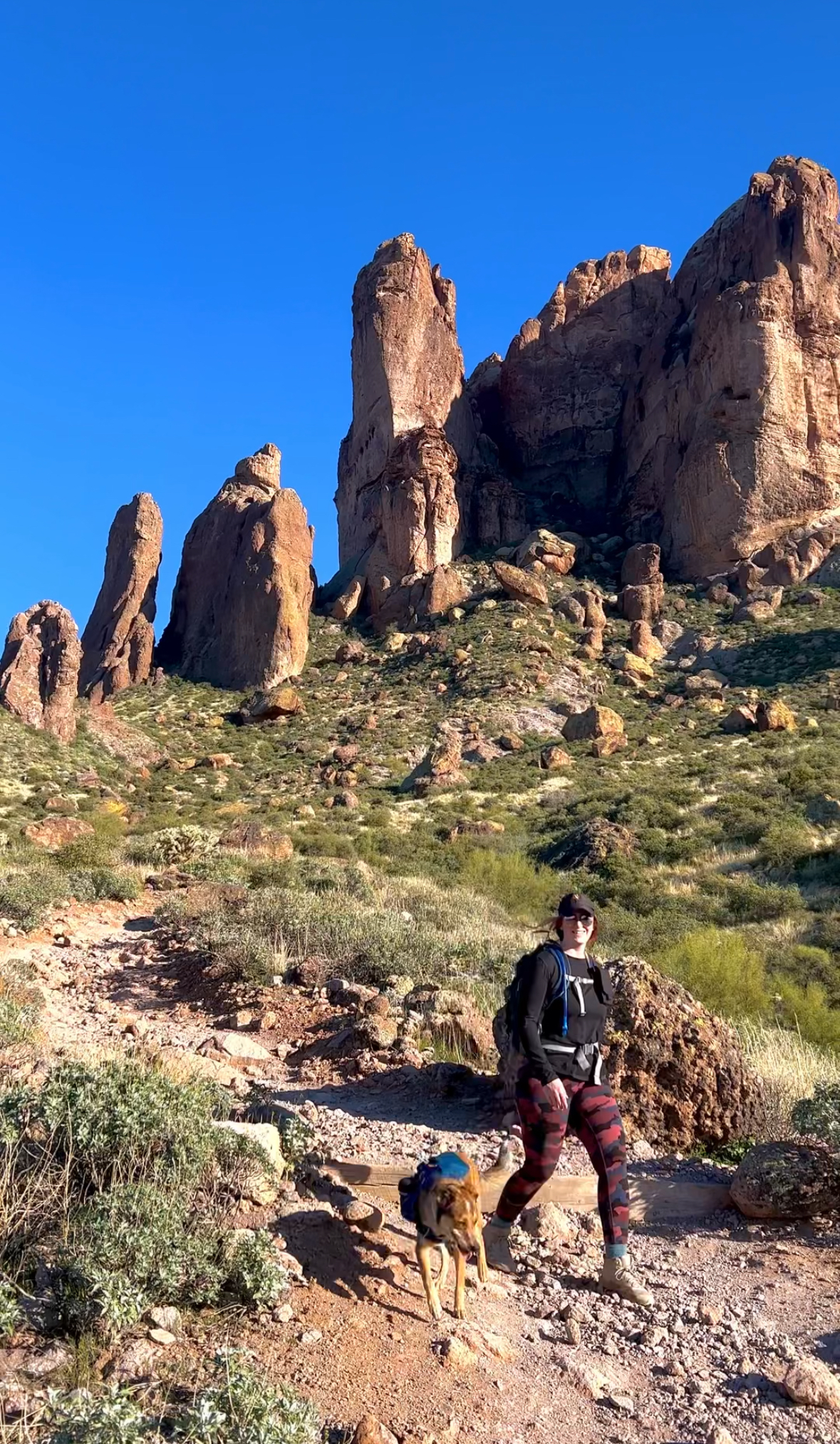 girl and dog hiking on a desert trail