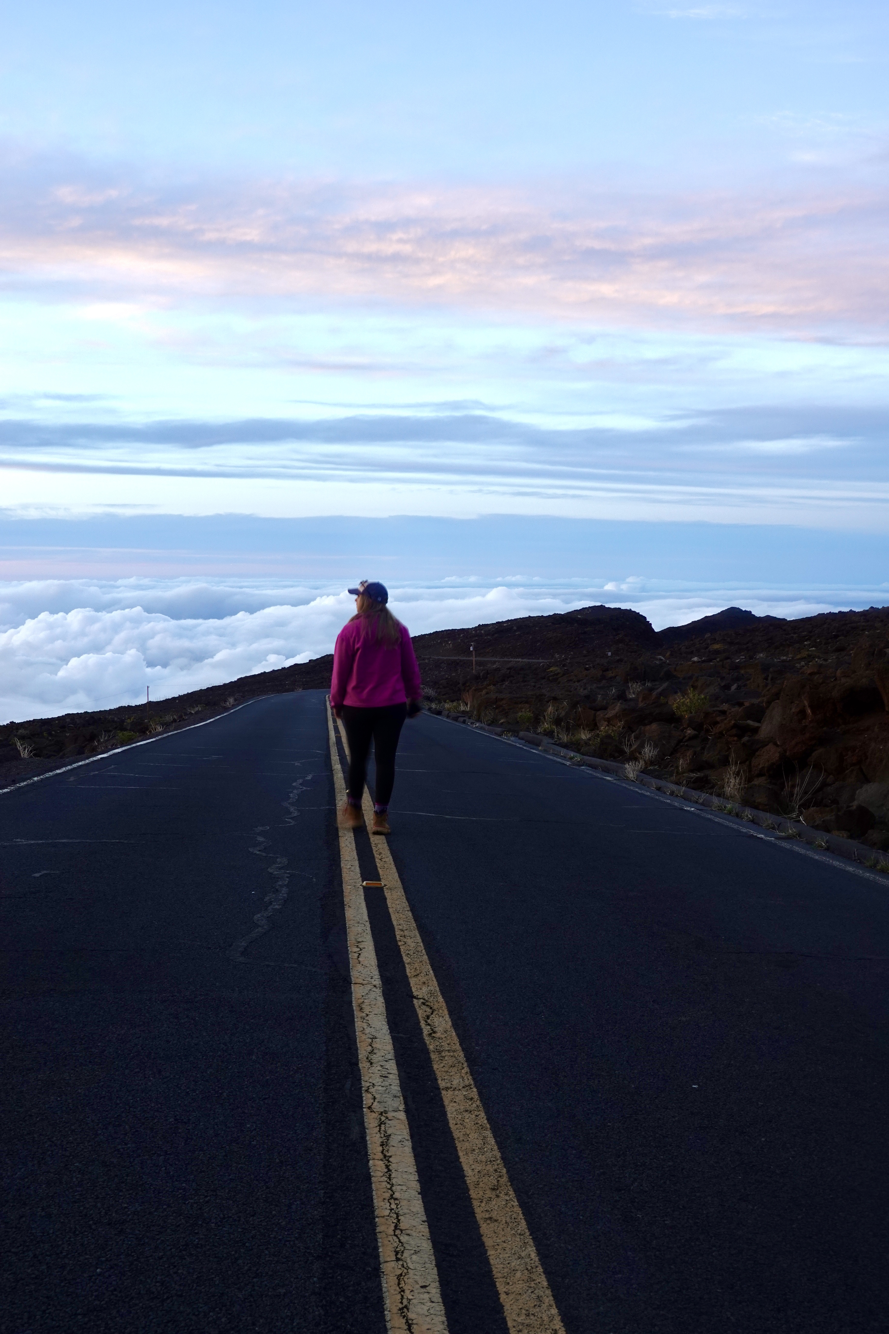 girl in pink standing on a road above the clouds