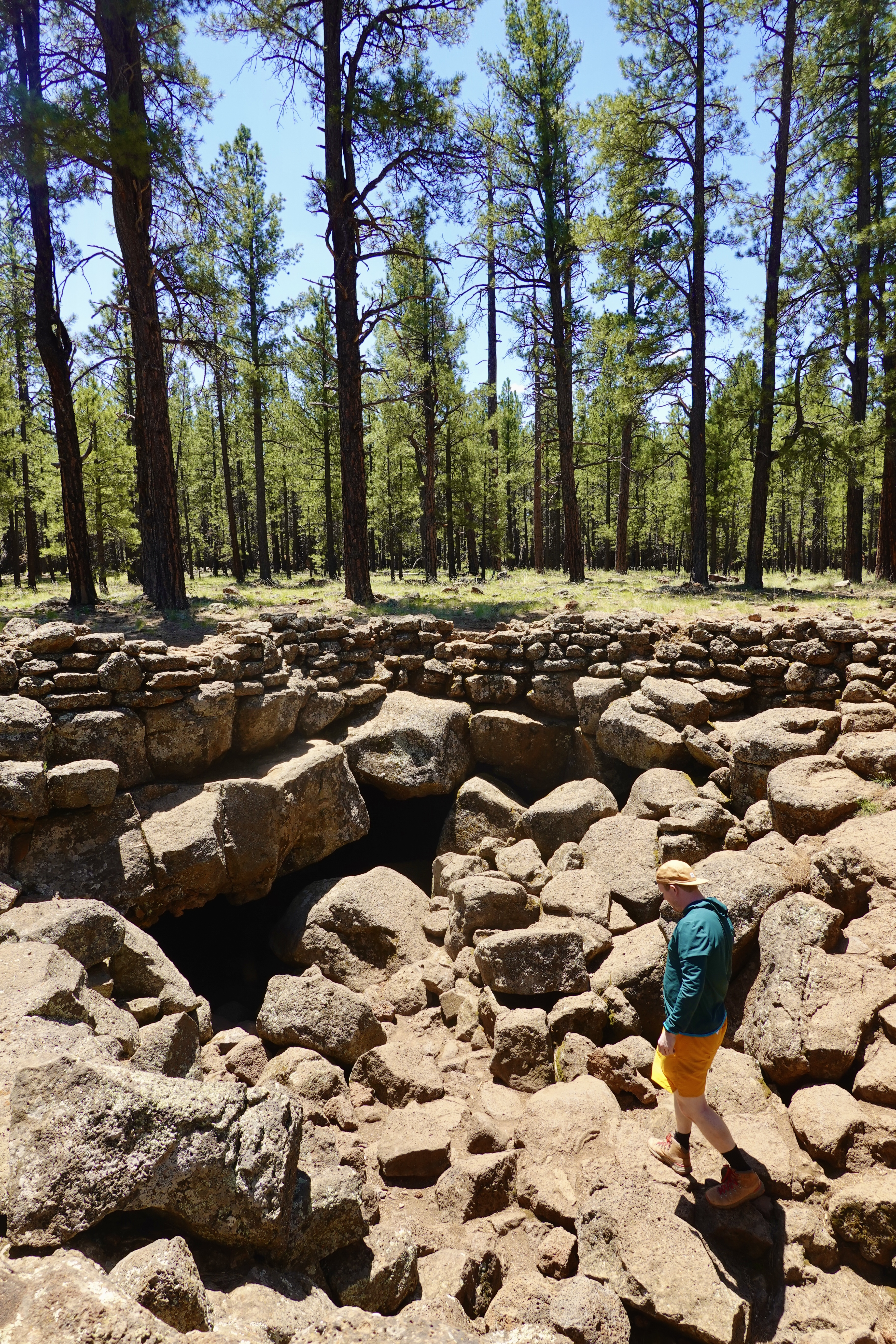 man walking into a cave in the forest