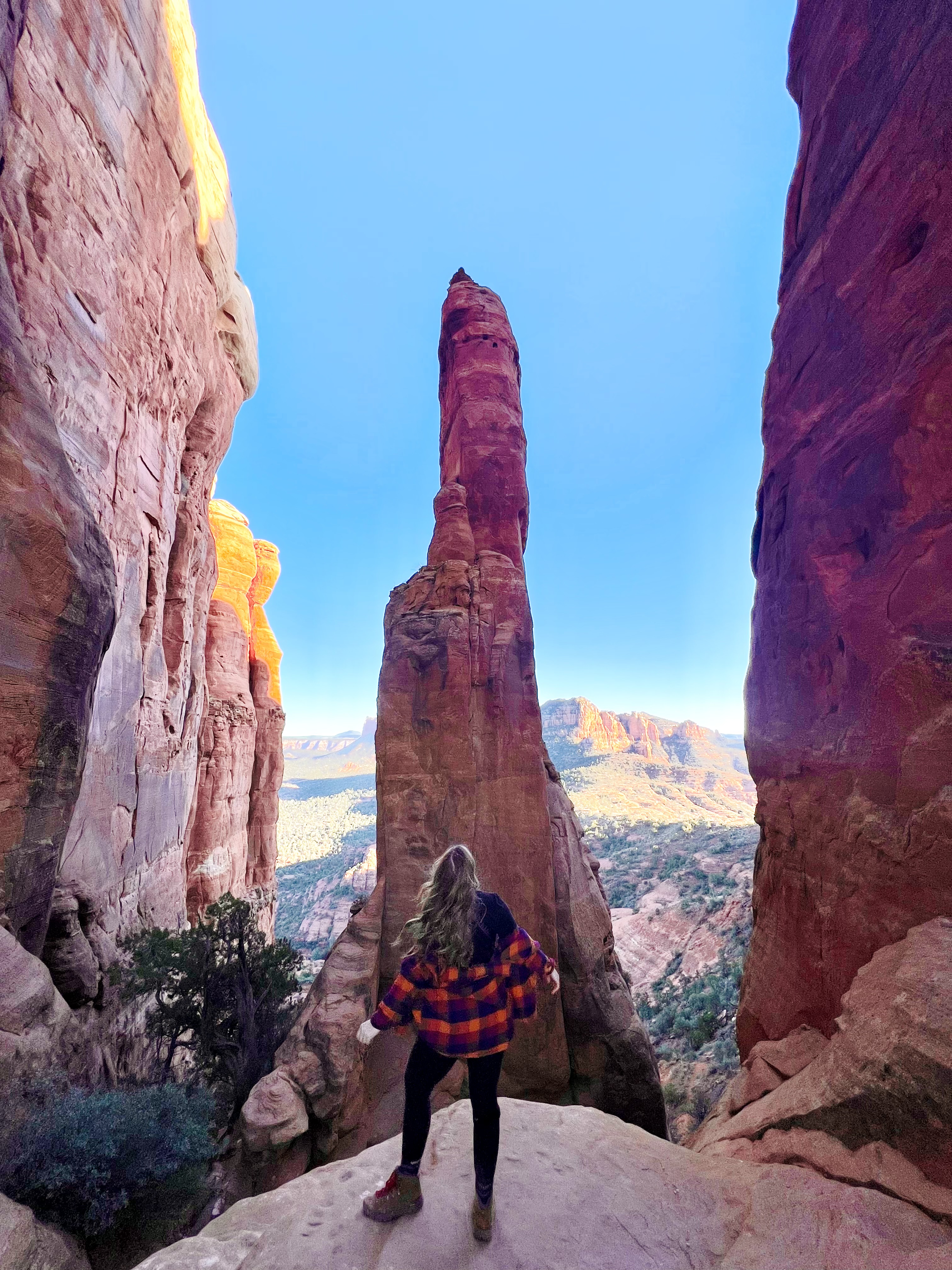 girl standing wearing a plaid on red rock on a blue day