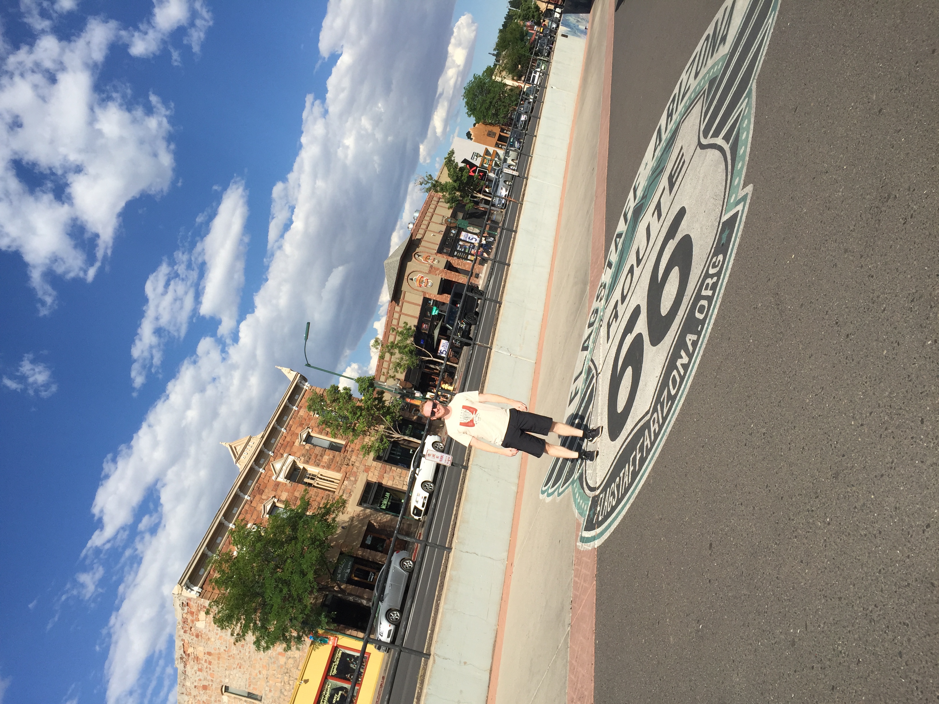 Man standing by a route 66 sign on the road in flagstaff