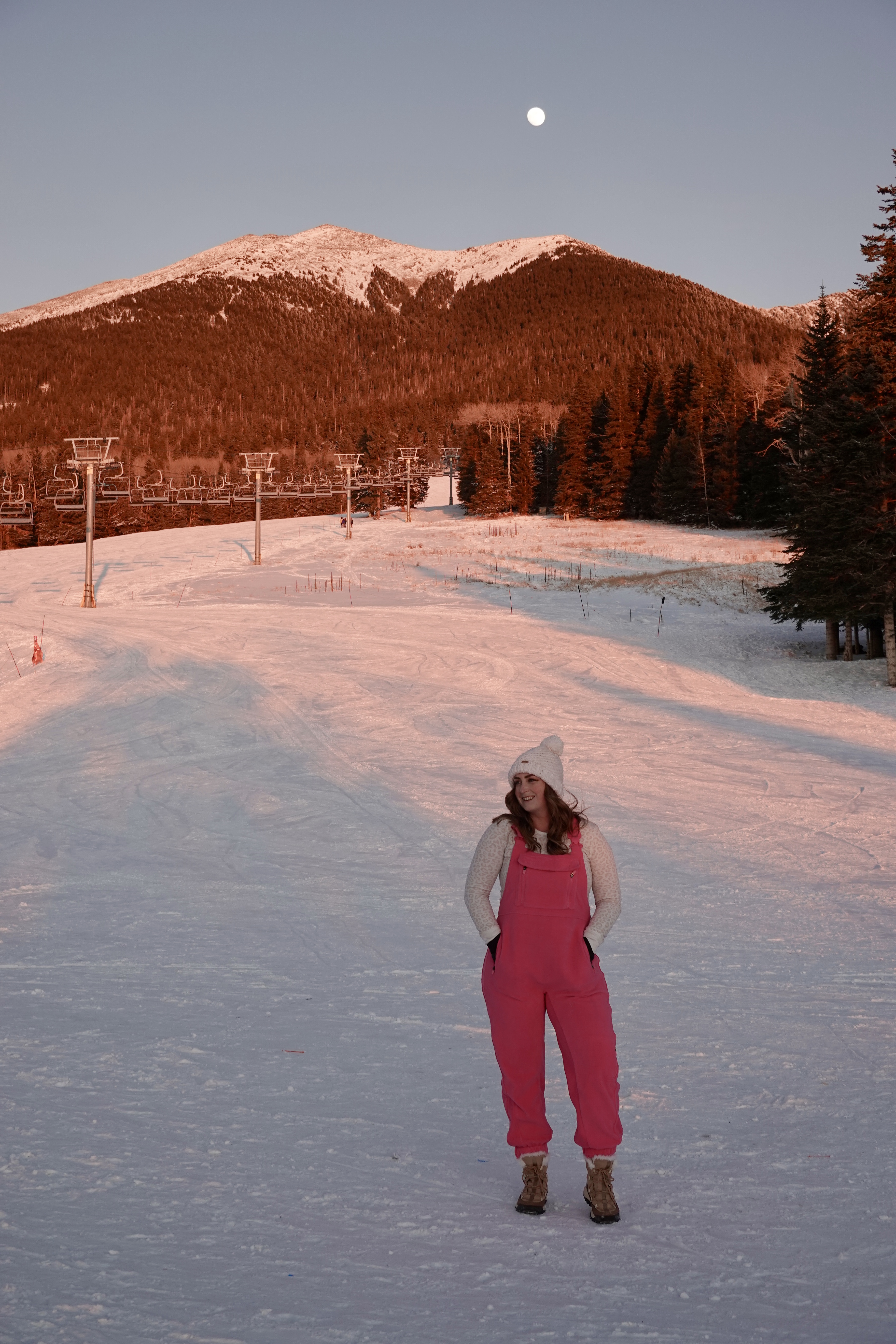 photo of a girl in pink overalls in the snow at sunset