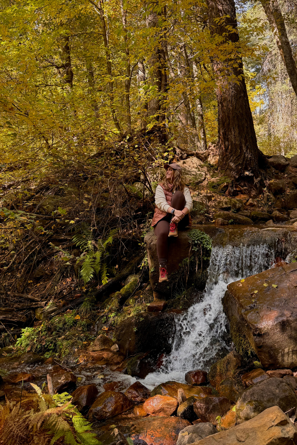 girl sitting by a waterfall in the fall colors