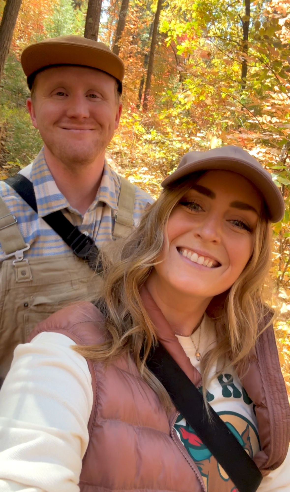 a couple smiling in front of yellow leaves