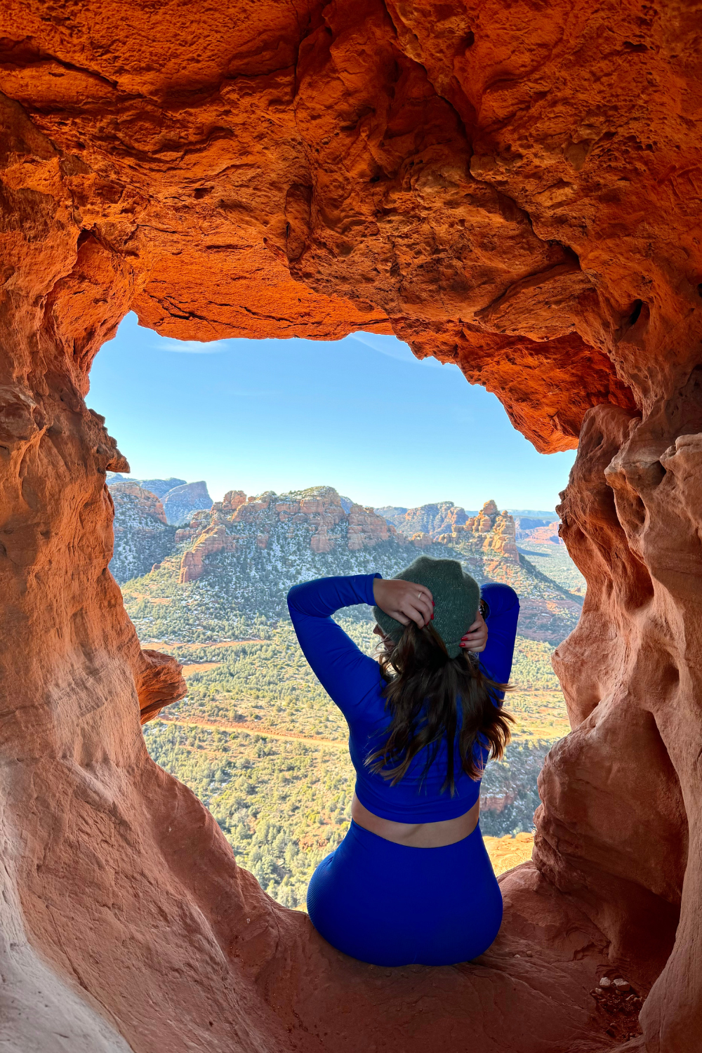 girl in blue sitting in a cave overlooking sedona