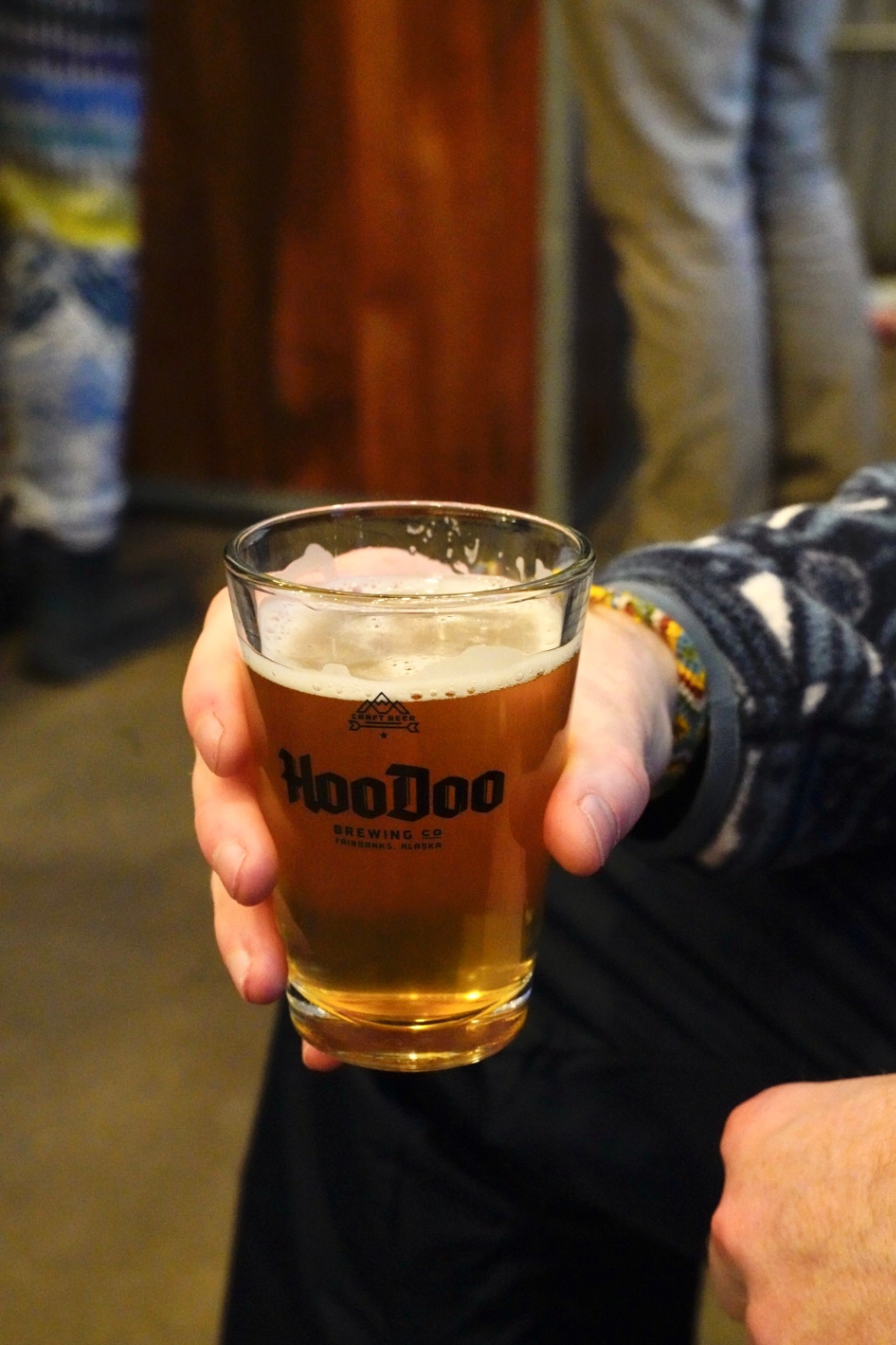 photo of a man at a brewery in fairbanks alaska holding a cup saying hoodoo brewing