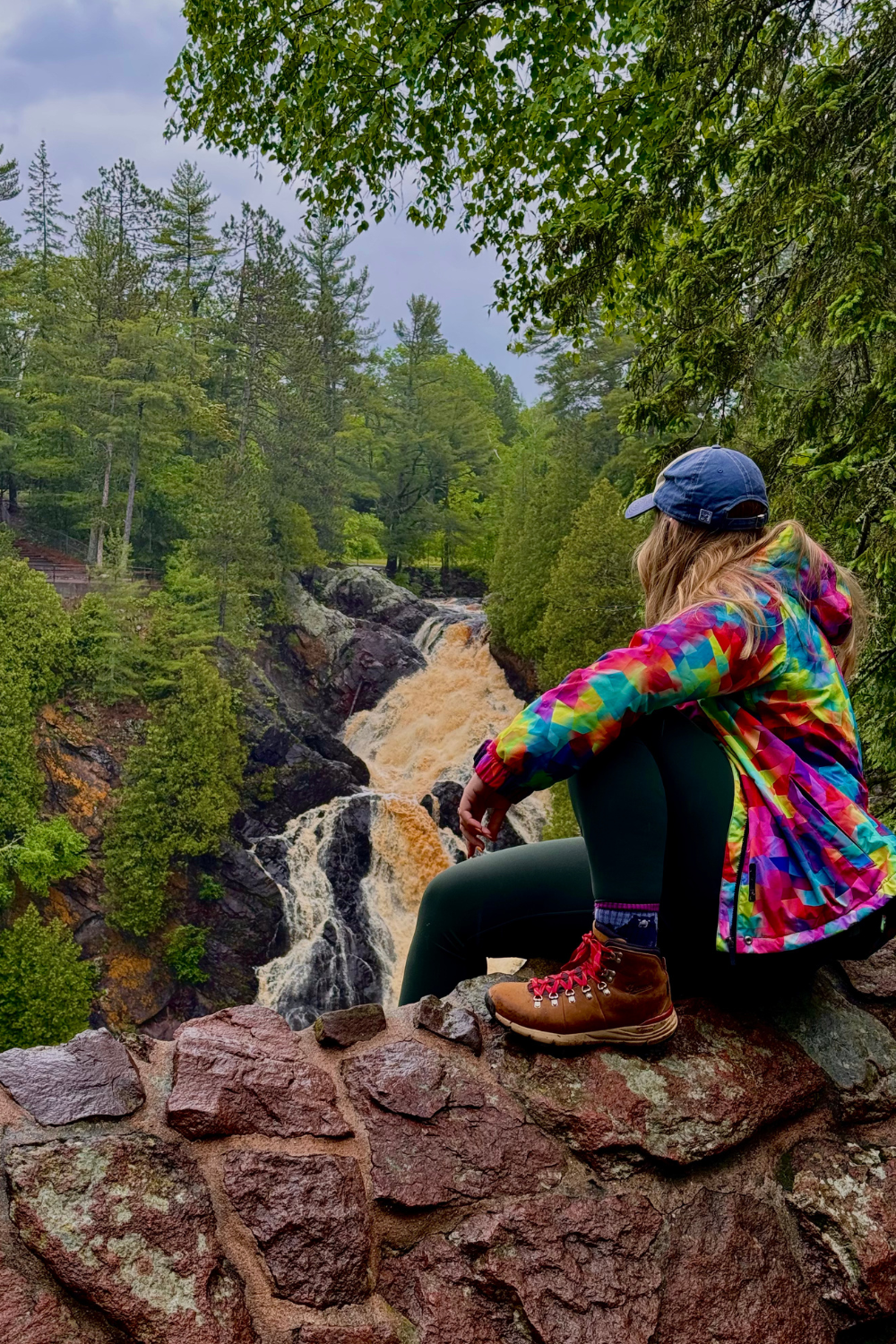 bayfield wisconsin photo of a girl in a colorful jacket sitting overlooking a waterfall