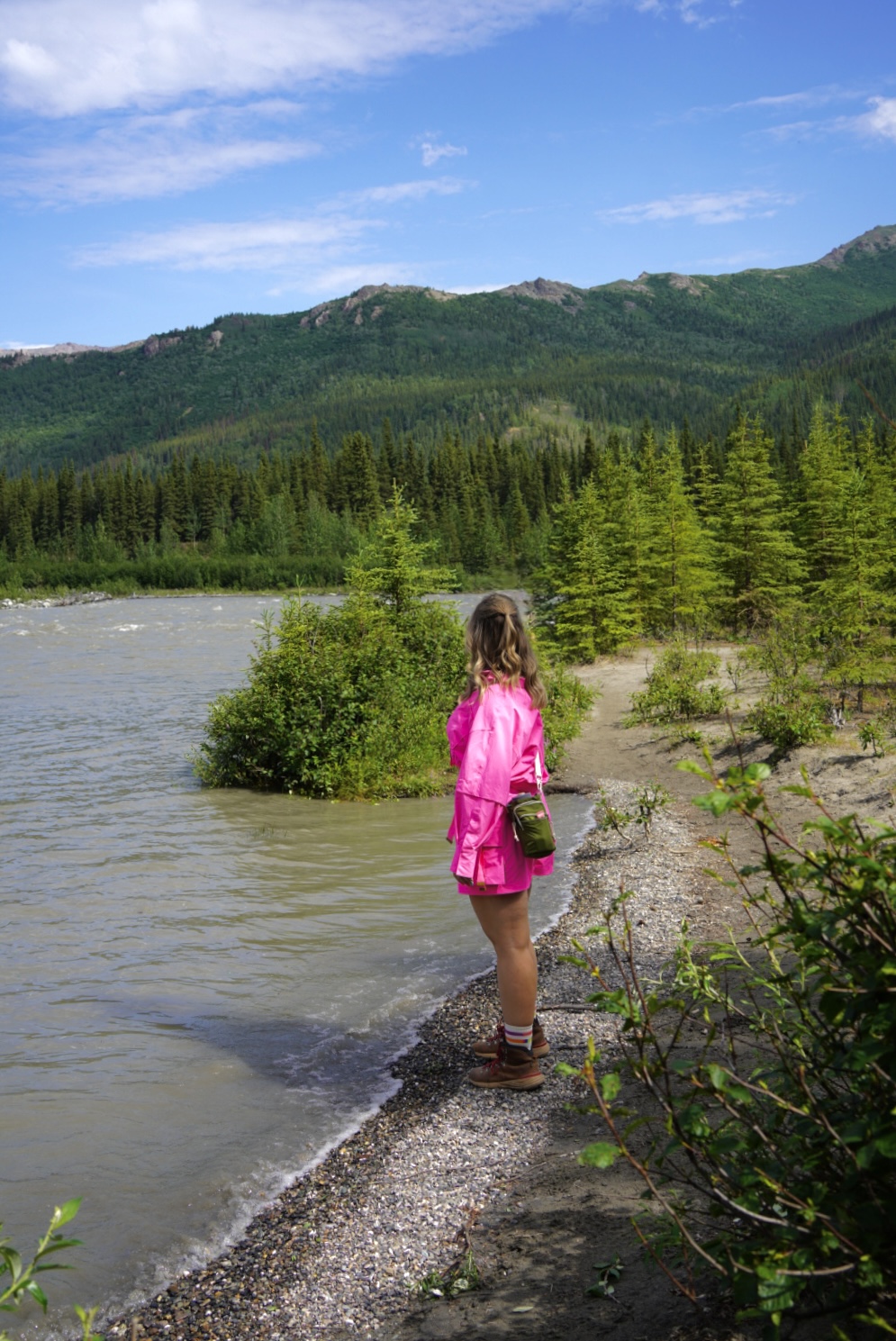 photo of a girl in pink by a river int he mountains
