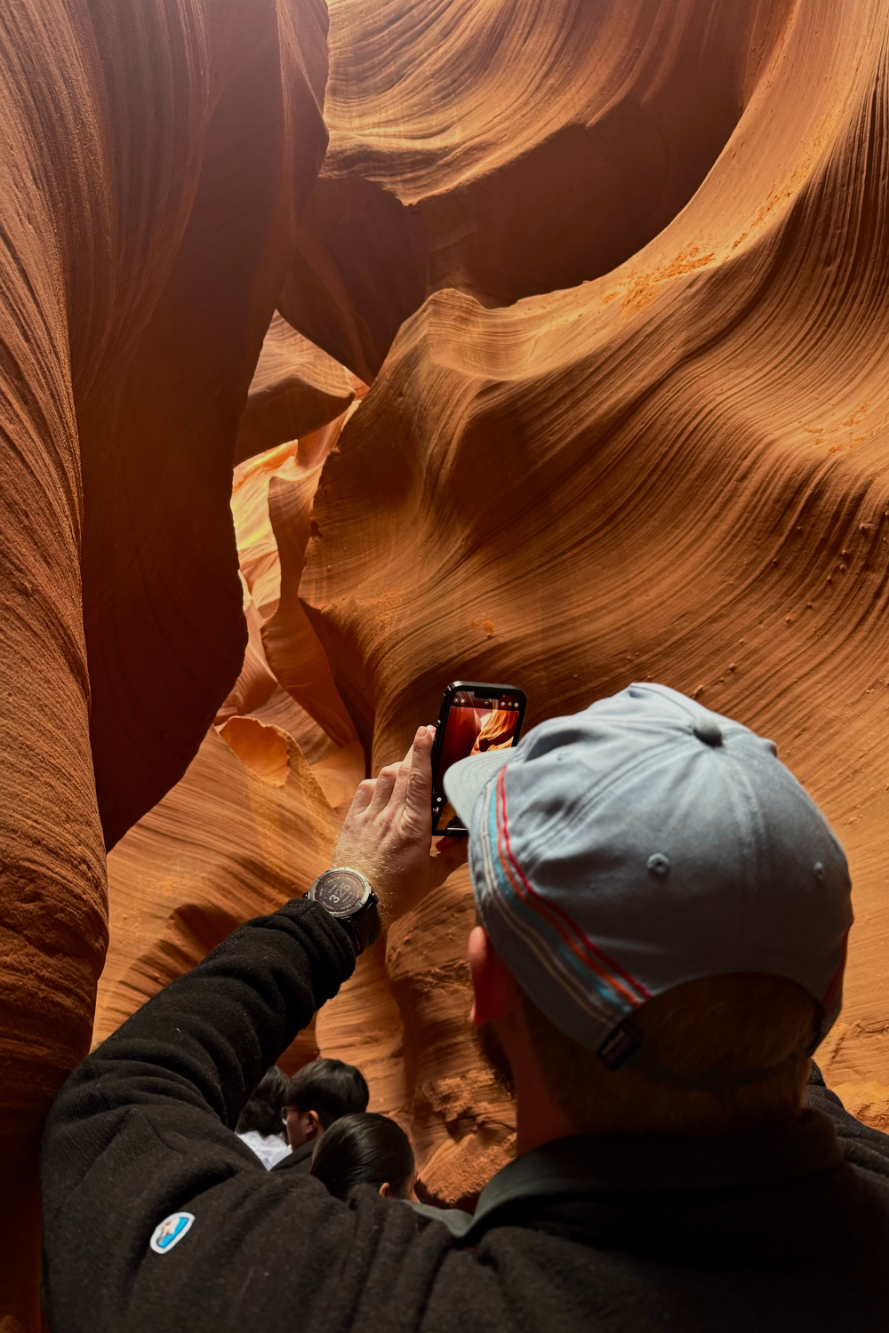 photo of a man taking a photo of a an orange slot canyon