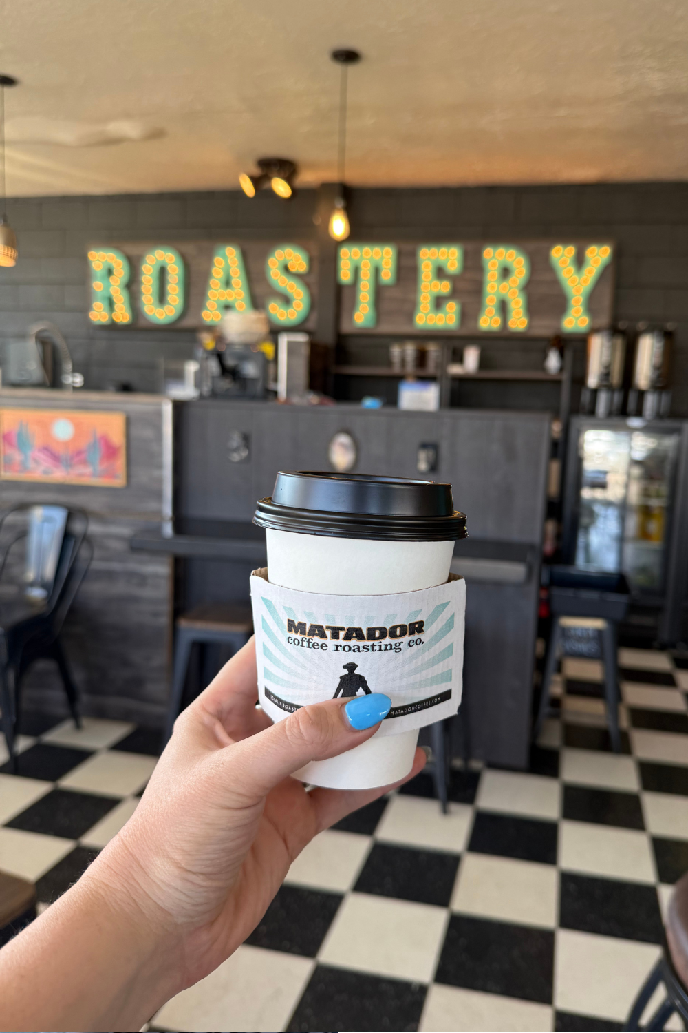 photo of a girl holding up a coffee cup with a sign reading roastery