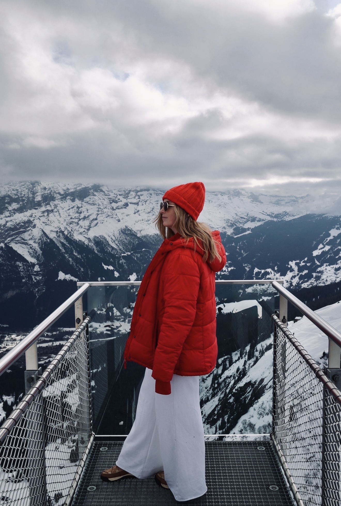 girl in red and white overlooking snowy mountains