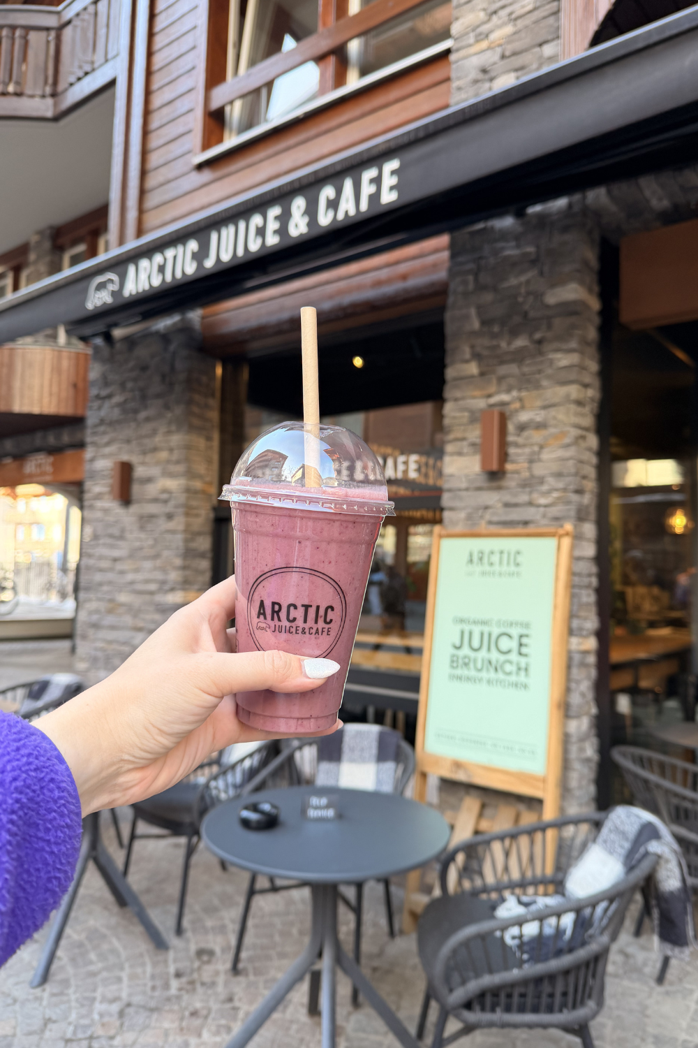 photo of a girl holding up a smoothie in front of arctic juice & cafe